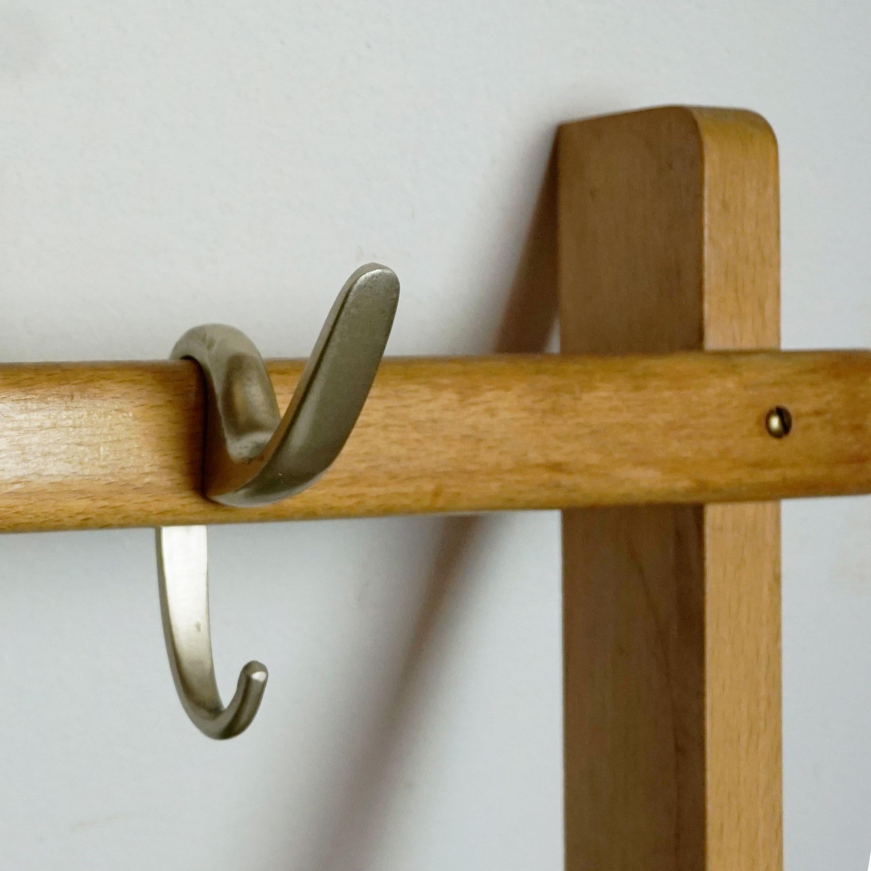 Sought after rare Austrian midcentury wall-mounted coat rack designed by the Austrian architect and designer Carl Auböck. It features a beechwood frame with six movable anodized aluminum hooks. It is in beautiful original vintage condition.