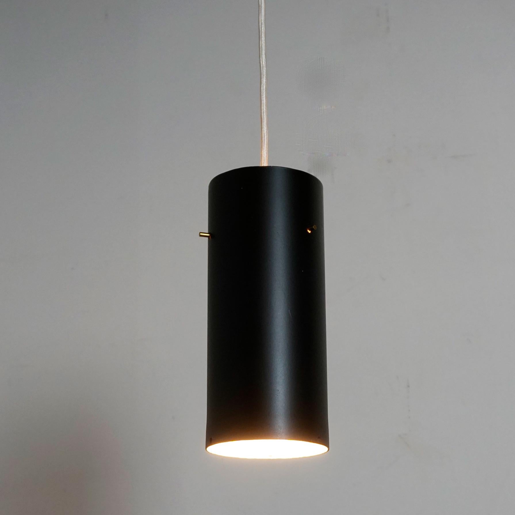This beautiful zylindrical shaped pendant lamp was designed and manufactured by J. T. Kalmar Vienna in the 1960s. It features a black lacquered shade with white interior and one E 27 light socket and small brass details.
It´s clear and puristic