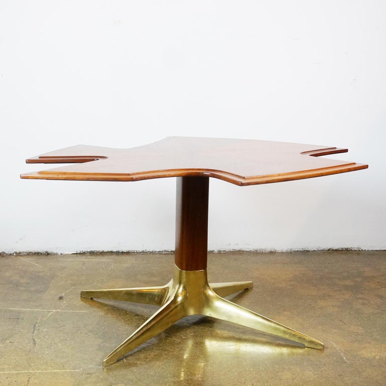 This outstanding coffee table or side table or sofa table was designed by the Austrian architect and designer Oswald Haerdtl and manufactured in the 1950s in Vienna. It features a heavy brass foot and a walnut shaft and unusually shaped excellent