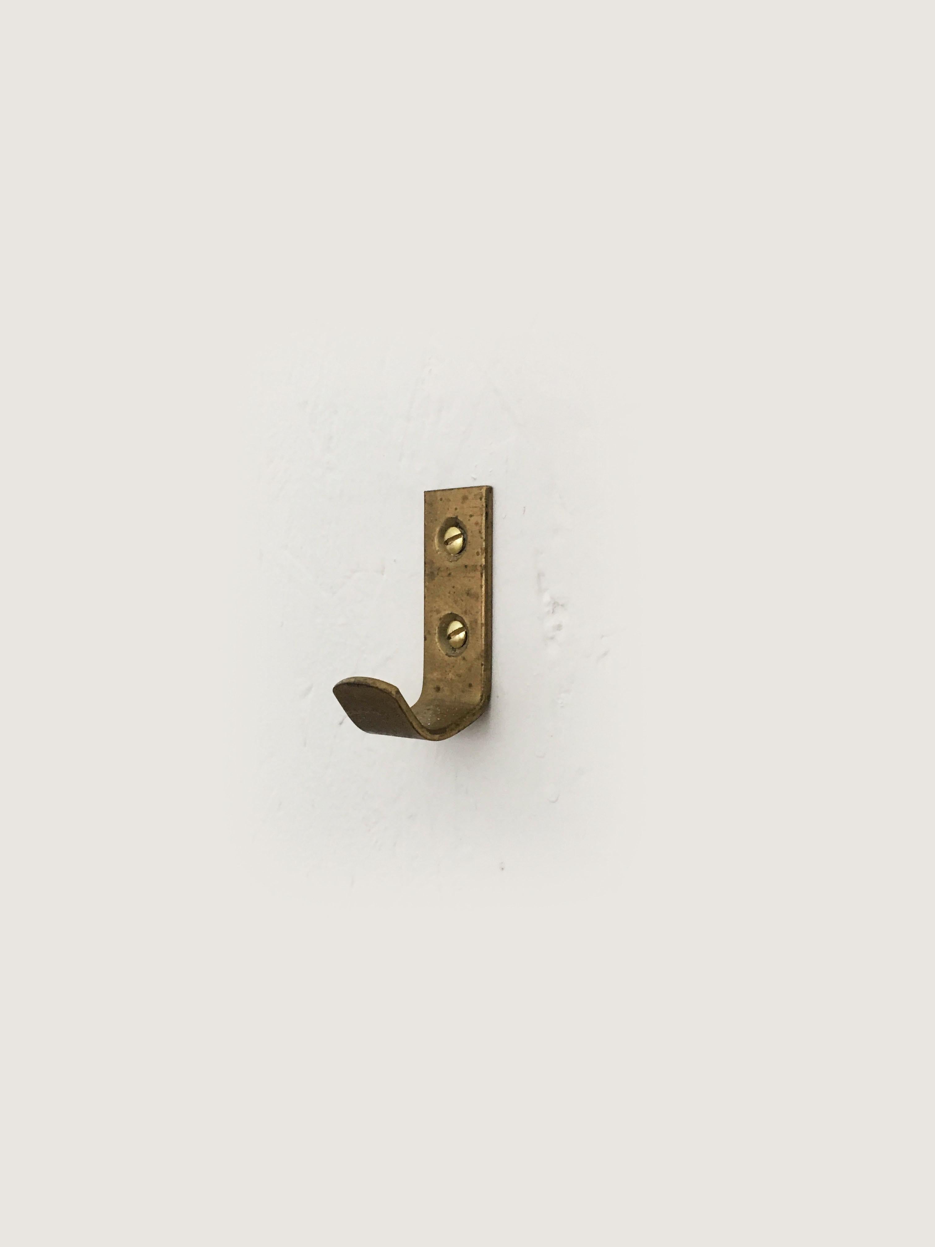 A set of 10 petite minimalist Austrian brass wall hooks, made of solid brass, executed in the 1950s by Hertha Baller, Austria. The size is perfectly suited for a bath or bedroom. In good condition, with gently worn patina. Priced as a set of 10