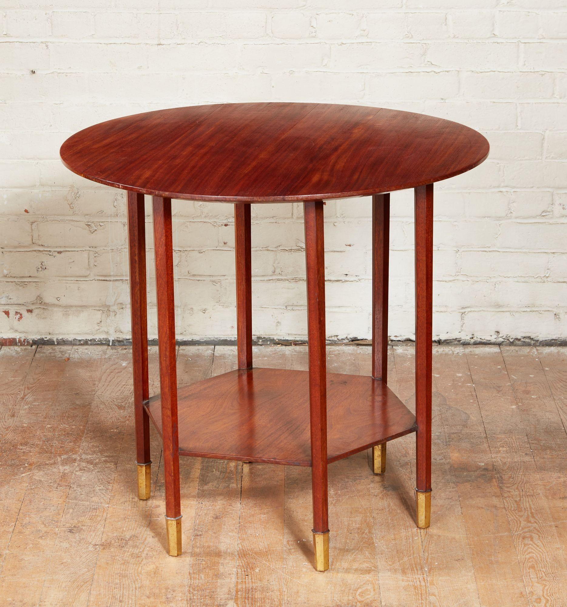 Fine and stylish mahogany table, early 20th century, the round top with under chamfered edge over six hexagonal tapered legs joined by hexagonal shelf, and standing on cast bronze hexagonal toe caps. Unsigned, but in the manner of the Wiener