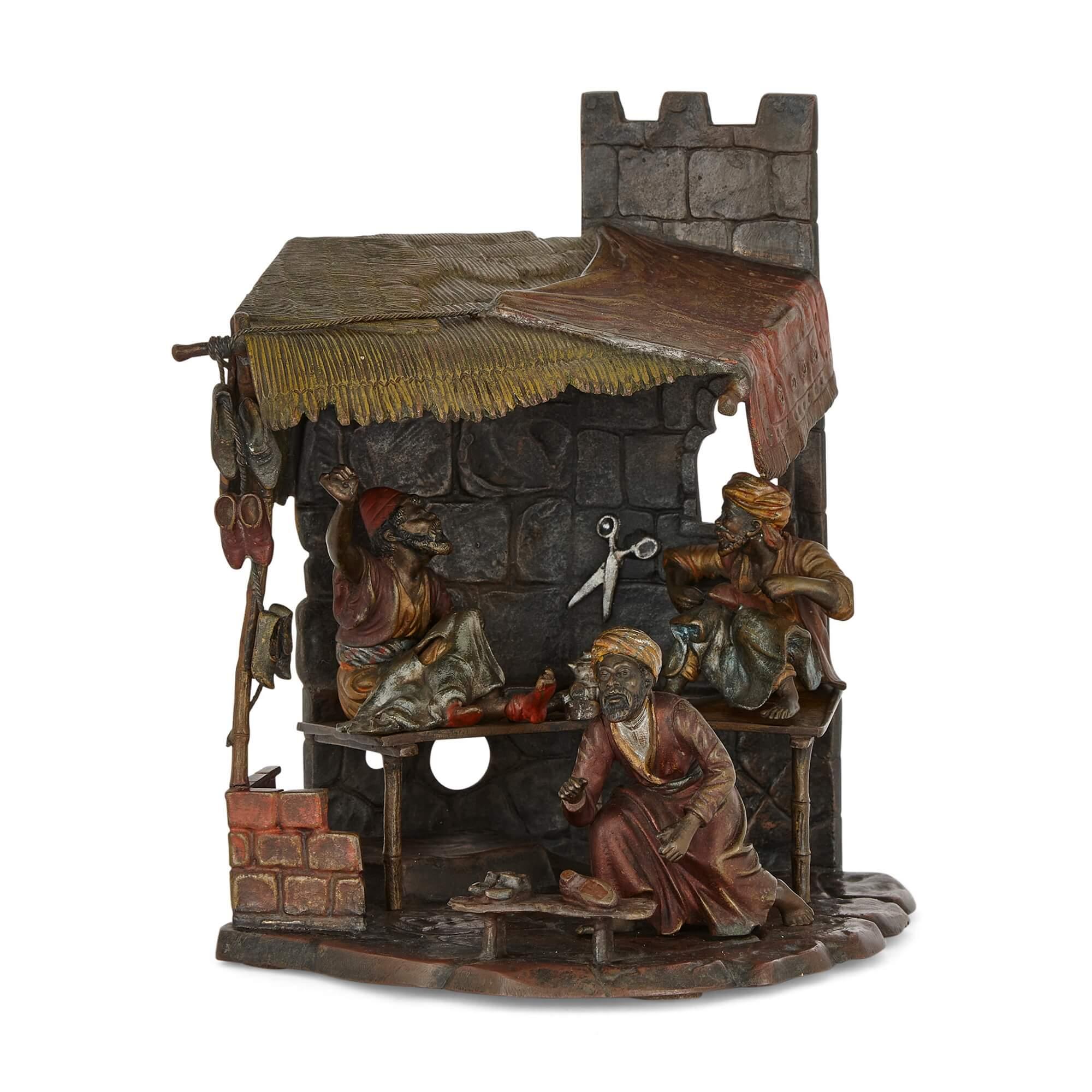 Austrian Orientalist cold-painted bronze lamp of a shoe cobbler 
Austrian, Early 20th Century 
Height 23cm, width 21cm, depth 16cm

The story presented by the makers of this sculptural lamp is set at a shoe cobbler’s workshop. Made in the