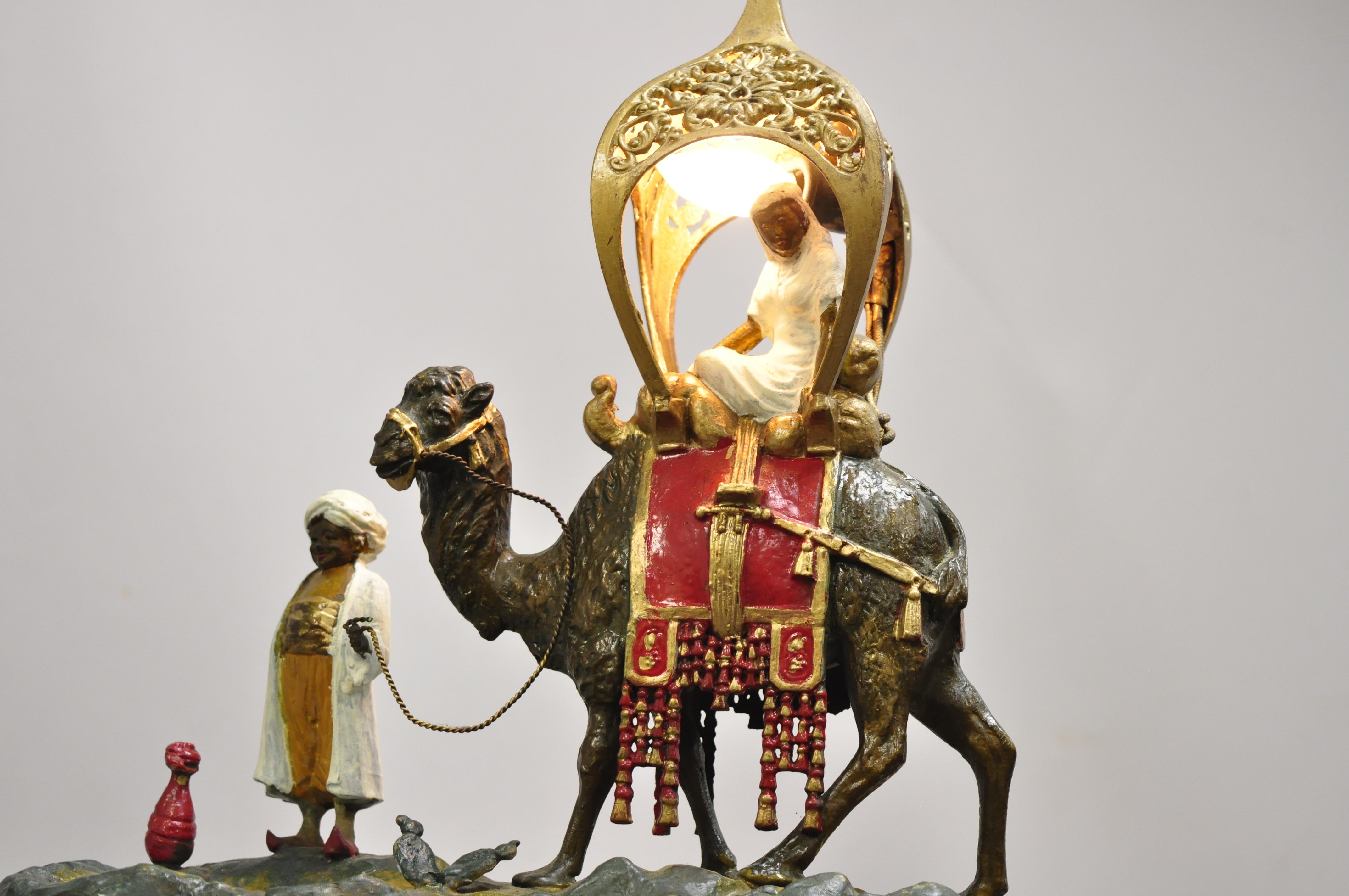 Antique Austrian Orientalist cold painted spelter man and camel watering hole table lamp. Item features cast metal construction, single light, depicts a camel with Howdah and attendant at a watering hole, very nice antique item, circa early to