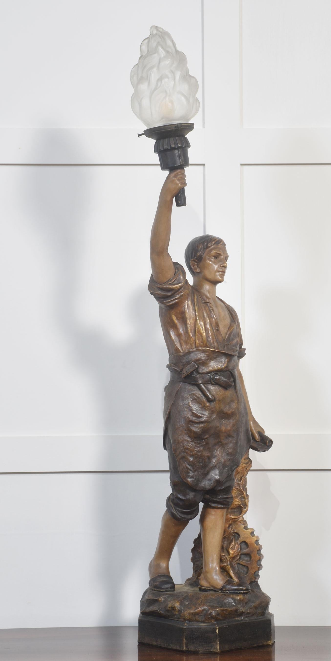 Austrian painted terracotta figural table lamp in the manner of Goldscheider, modelled as an artisan holding a torch aloft in his right hand signed Aug Ollo, fitted with frosted glass flame shade. The lamp has been rewired and