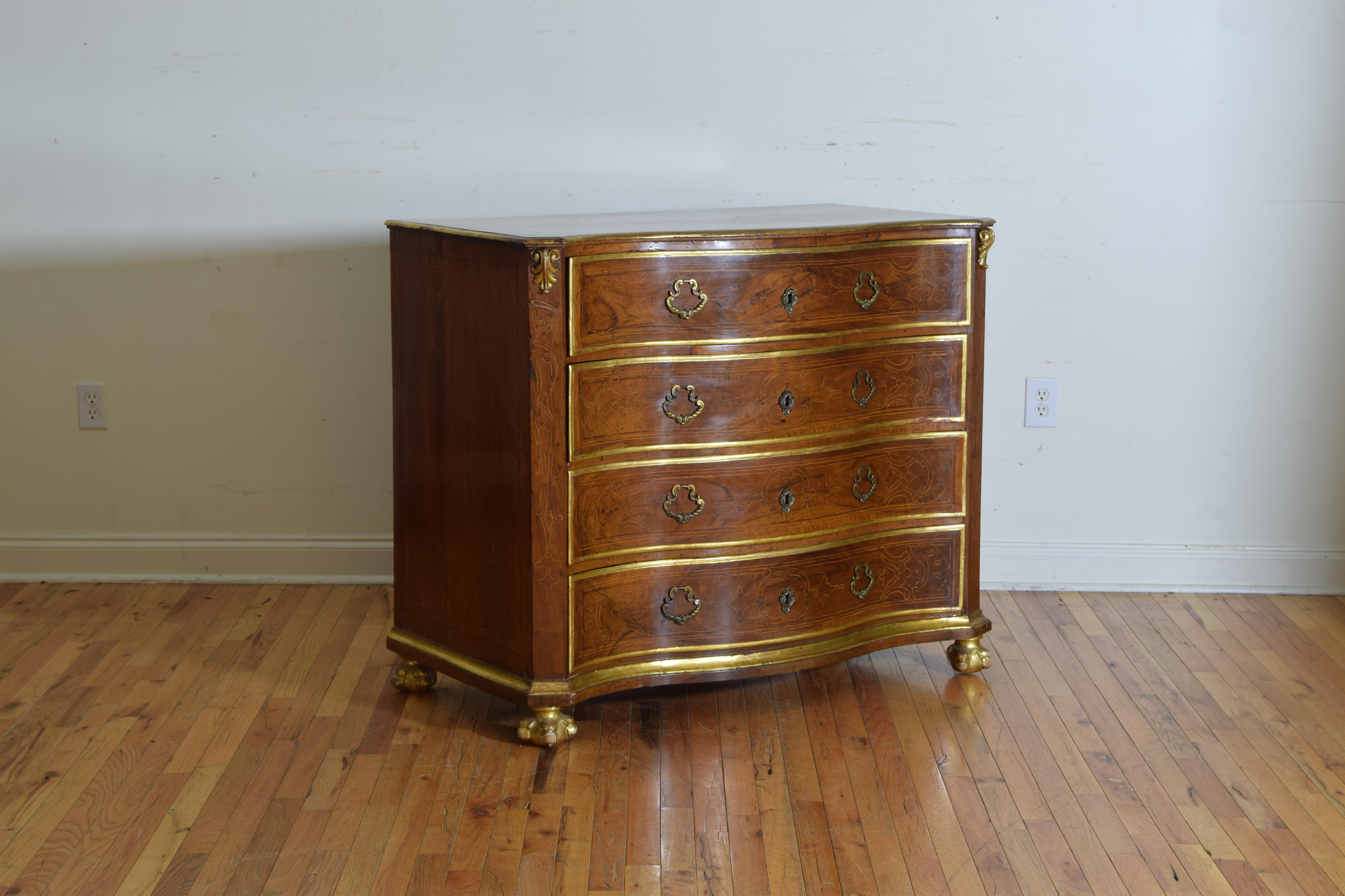 the serpentine shaped top with a double band inlay , the case with canted corners and applied giltwood carvings and a patterned band inlay housing 4 inlaid drawers, giltwood trim at top and around drawers and bottom of case, raised on gilded ball