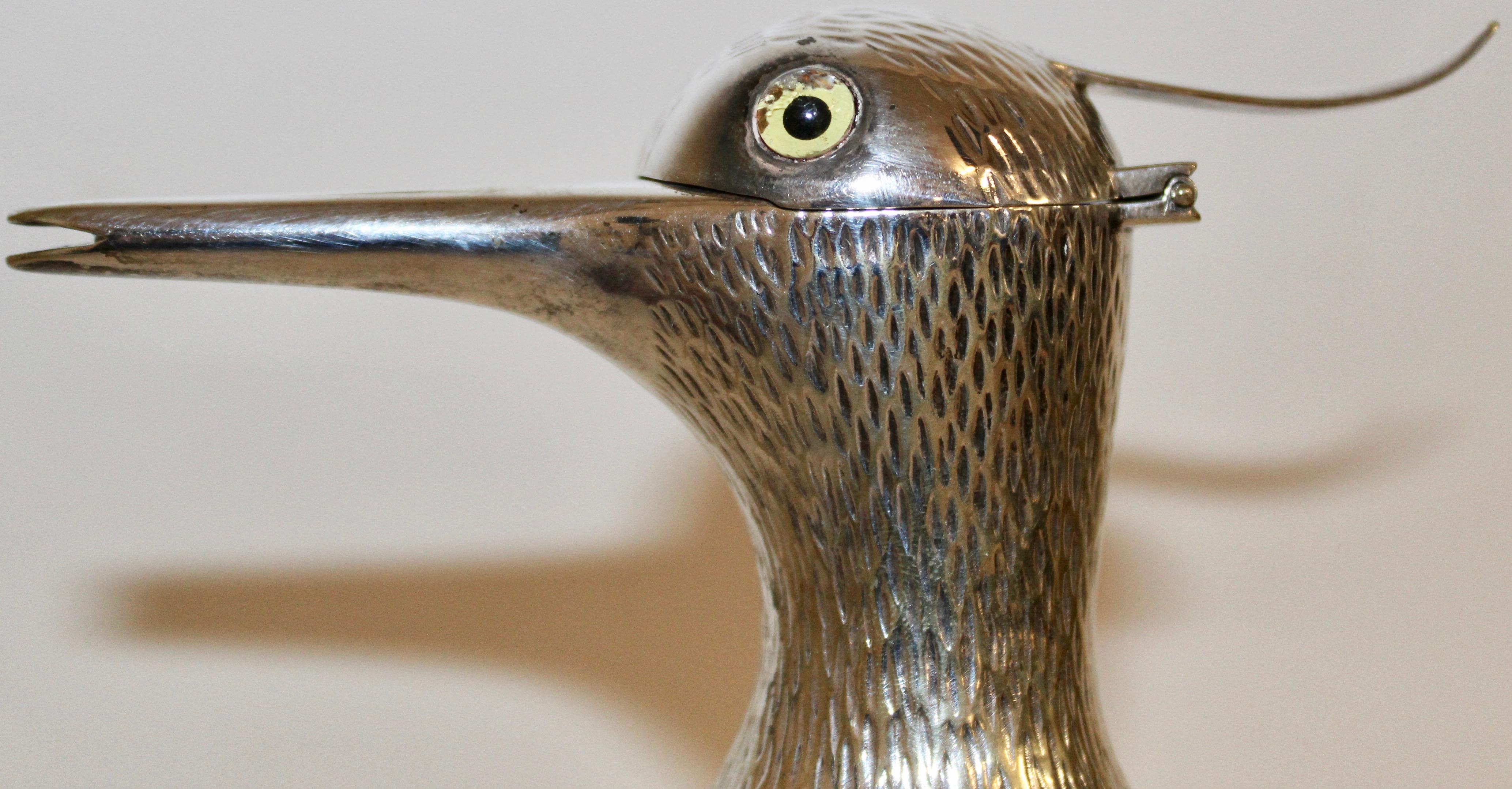 An Austrian glass and silver plate novelty decanter in the form of a bird, the head in silver plate, with a long hollow beak used for pouring from the 1930s. The lid in the shape of a hinged head, complete with glass eye. The silver plate neck with