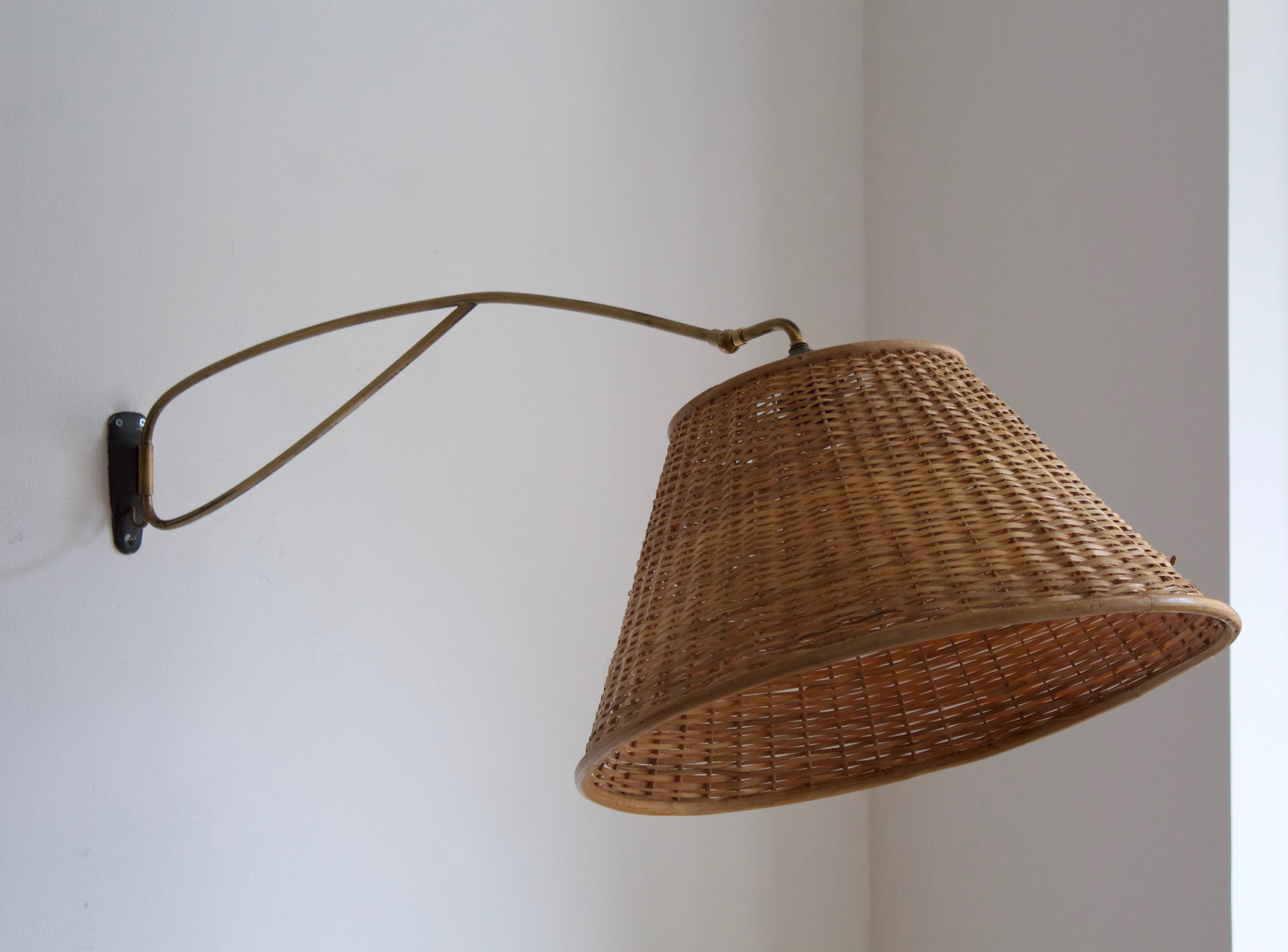 An adjustable functionalist wall light. Designed and produced in Austria, c. 1950s. In brass. Assorted vintage rattan lampshade.

Dimensions stated measured with lampshades attached.