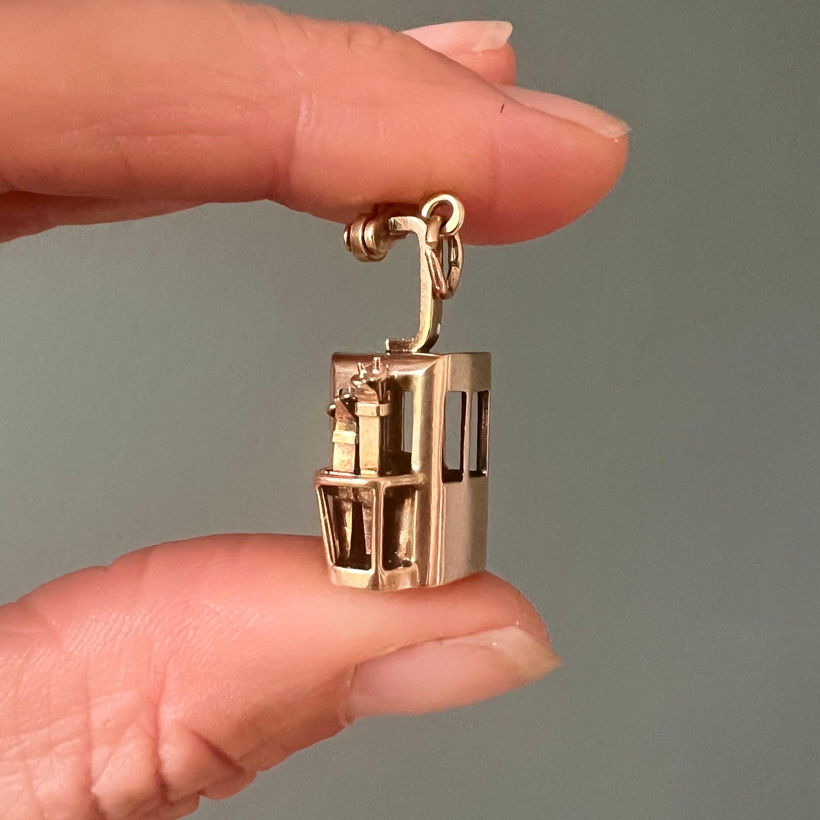 Un affascinante ciondolo vintage a forma di gondola, finemente realizzato in oro giallo 14 carati. Questa miniatura tridimensionale cattura l'essenza di una classica funivia alpina con notevoli dettagli, completa di finestrini aperti e piccoli sci