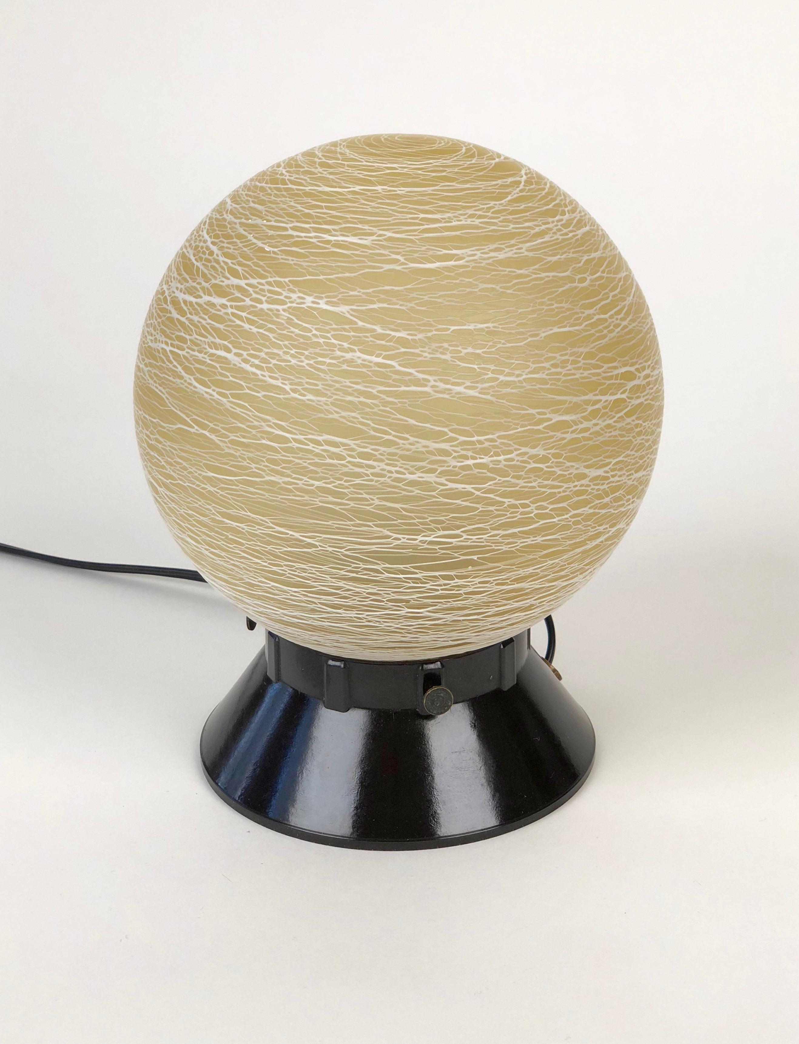 Austrian table lamp from the 1930s, is composed of a Bakelite base with a glass ball.
The pattern on the ball is made up of erratic lines that criss cross the surface accenting the round of the form.