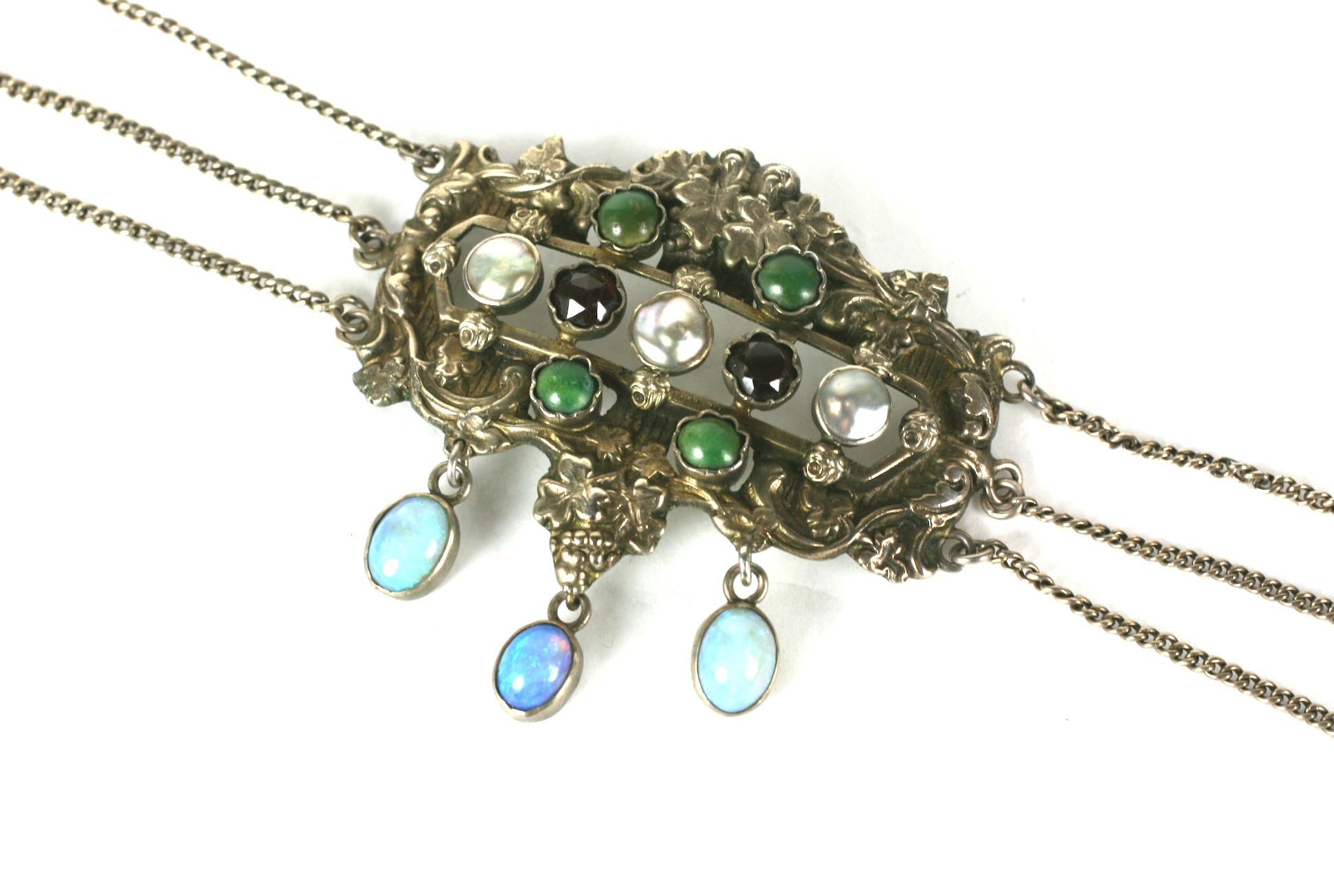 19th Century Hungarian necklace of gilt silver with jeweled central plaque of garnets, mother of pearl, green turquoises with 3 opal drops. Motifs include vines and grape clusters.
3 chains hold the plaque from each side and have lozenge shaped