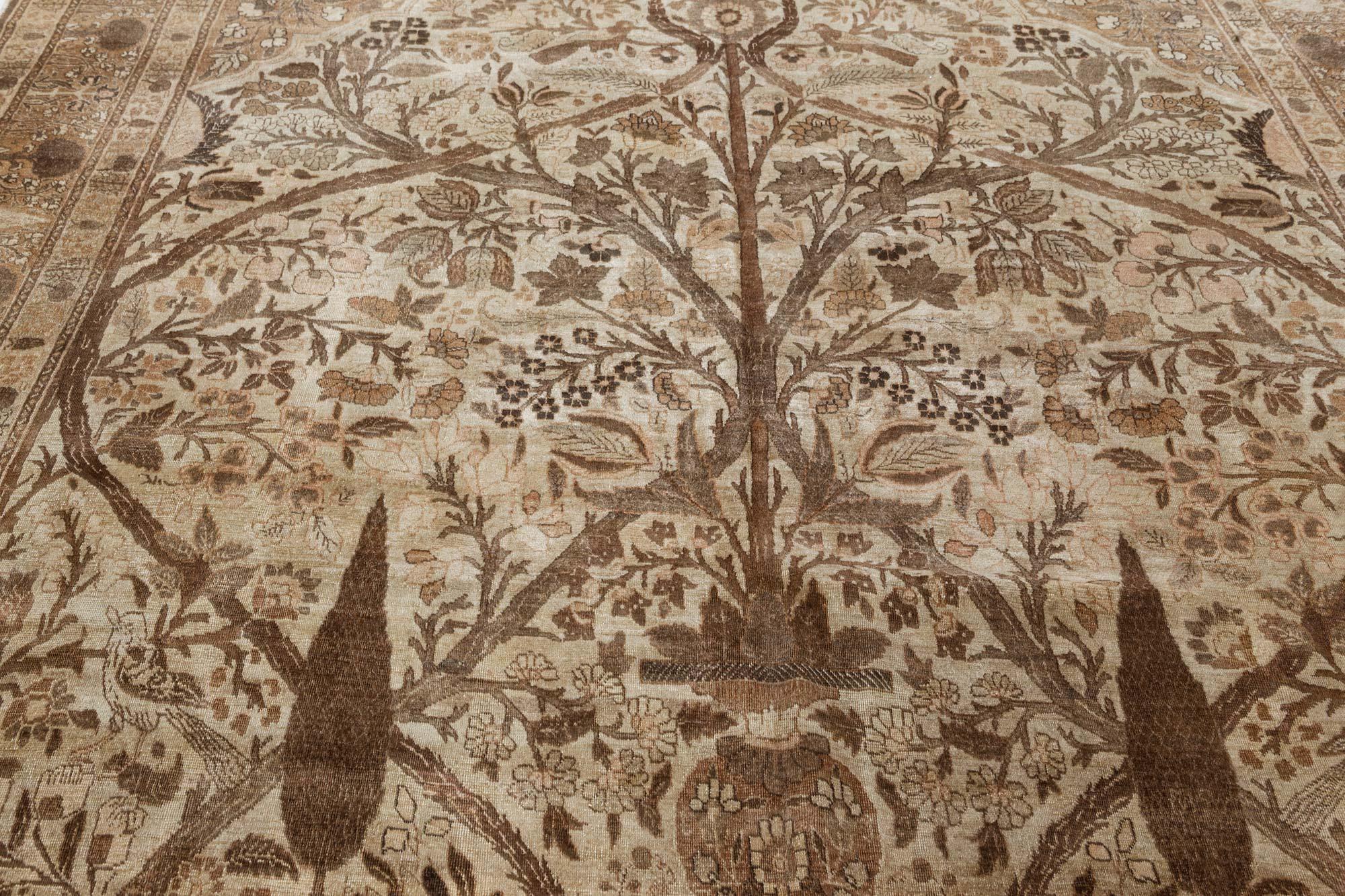 Autehntic Persian Tabriz Handmade Wool Rug
An unusual early 20th century Persian Tabriz rug, having a sand field and a spacious garden design with flora and fauna overall framed by an large flowering tree and a large cocoa vine within a tan tree and