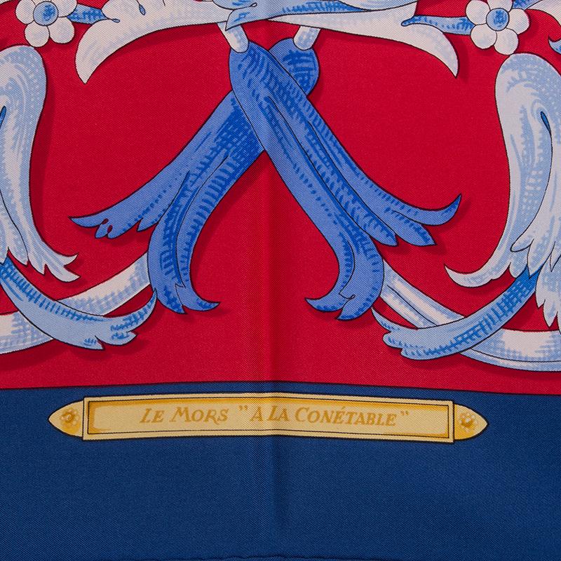 Hermes 'Le Mors a la Conetable 90' scarf by Henri d'Origny in red silk twill (100%) with navy blue border and details in gold, blue and white. Has been worn with minor signs of use. Overall in very good condition.

Width 90cm (35.1in)
Height 90cm