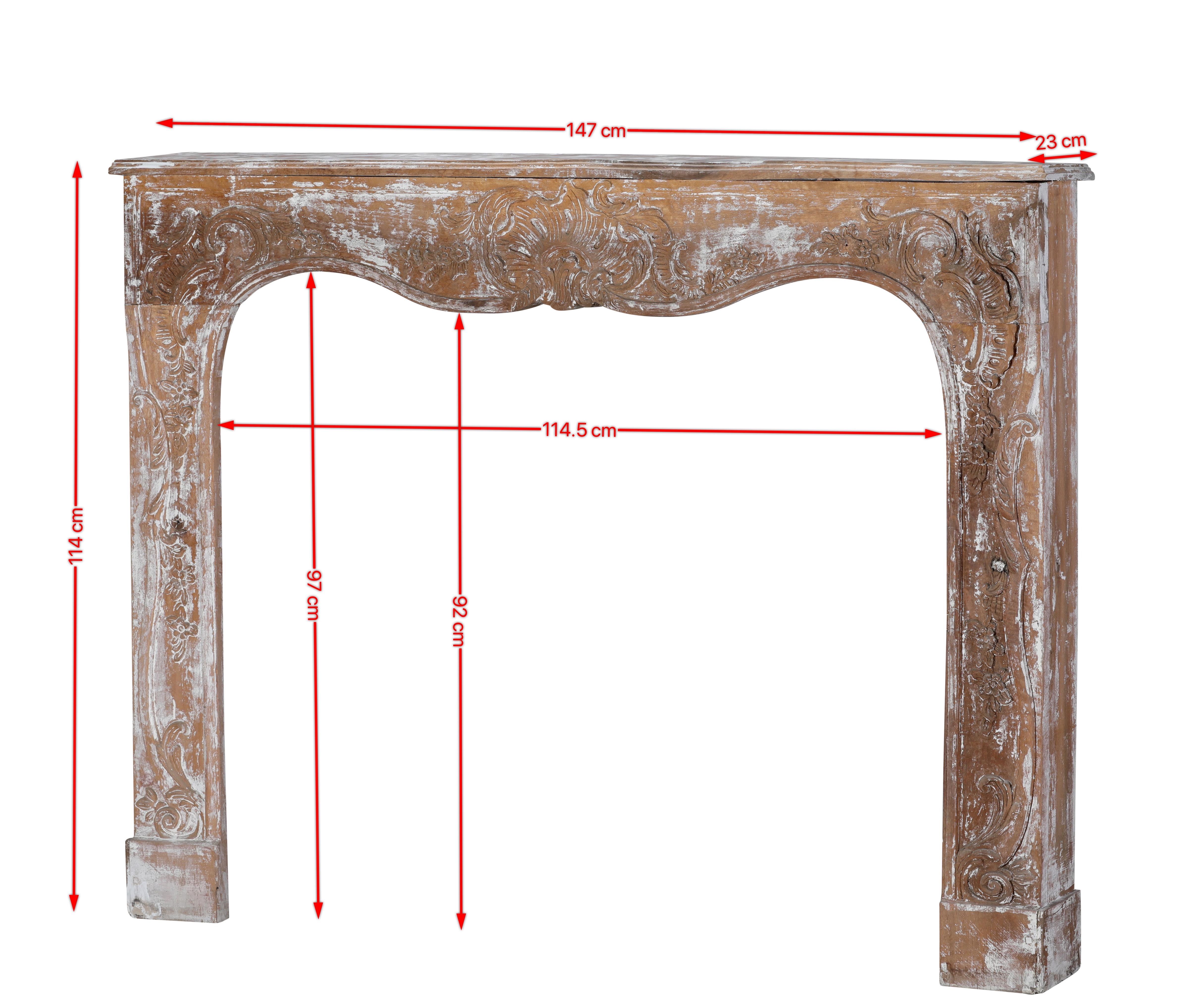 This authentic 19th-century Rococo-style wooden fireplace surround is a masterpiece of French artistry and craftsmanship.
Hand-carved from solid wood, the piece showcases the fluid elegance and naturalistic ornamentation typical of the Rococo