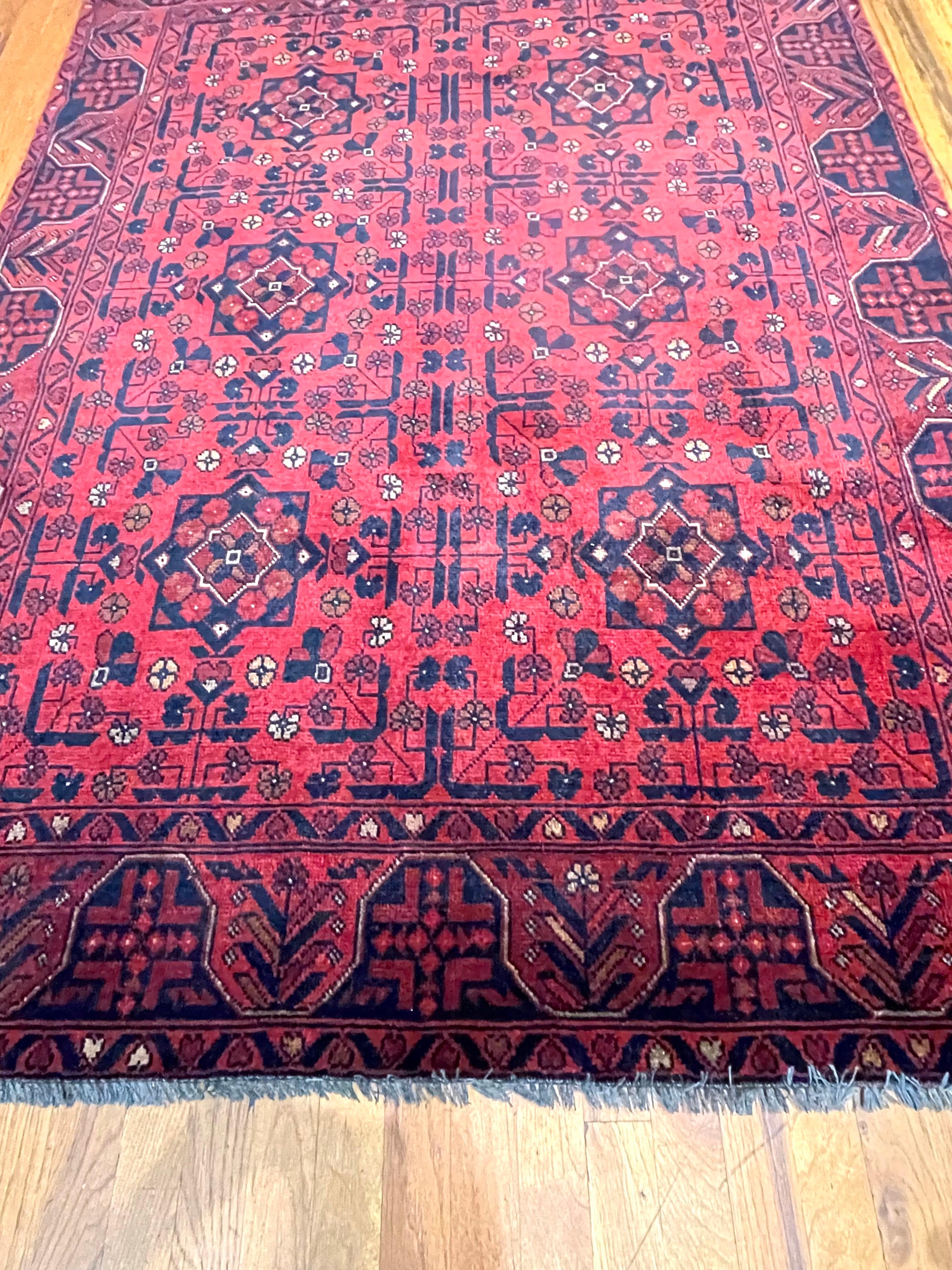 This rug is an Afghan Rug which is a workshop carpet woven by a weaving house in Afghanistan. Afghanistan has a rich history in the craft of rug-making. The design in this piece is tribal allover design known as Khal Mohammadi. A Khal Mohammadi rug
