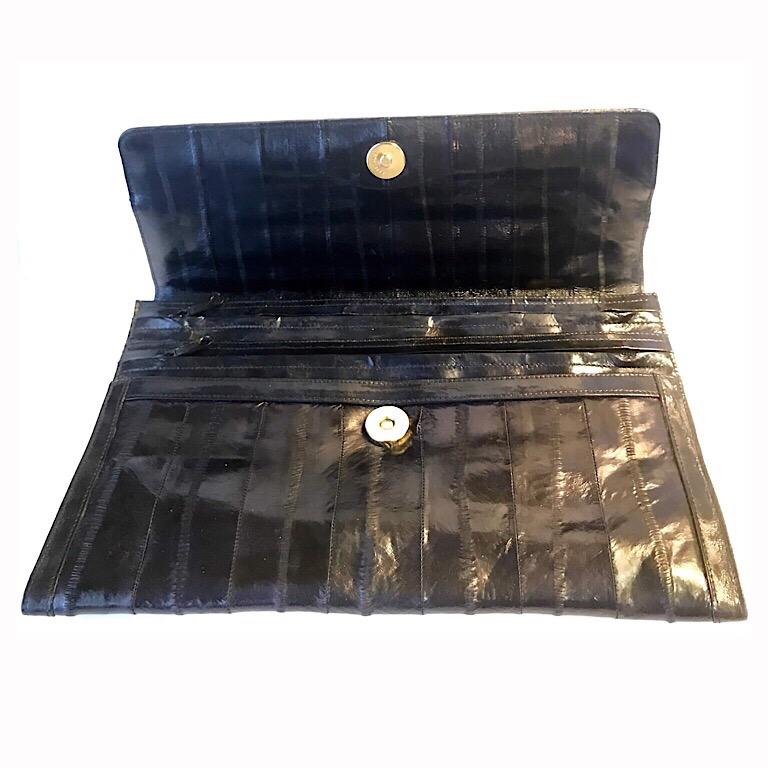 This elegant black clutch is made from eel. Its lovely tone and smooth sleek appearance make it a wise choice for a stylish evening out. It is small though practical and versatile with two inner zipped pockets. The detailed stitching on the exterior