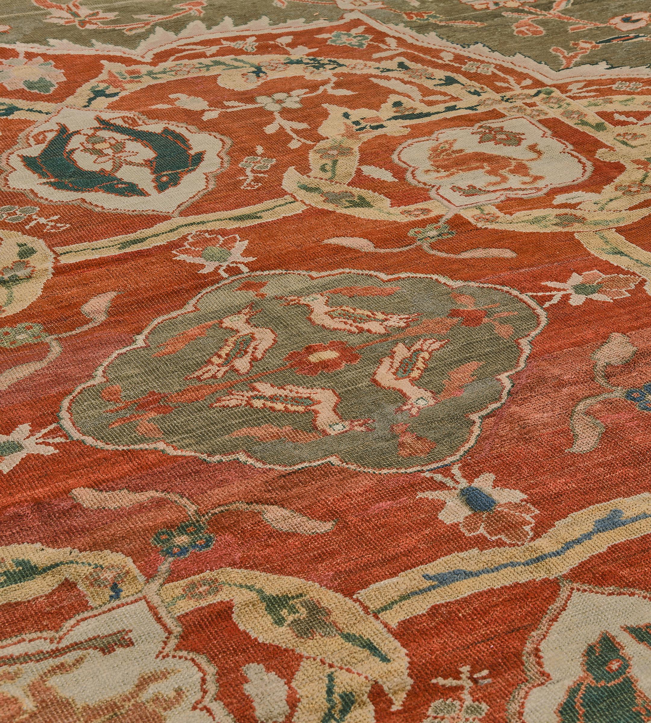 This traditional hand-woven Persian Ziegler Sultanabad rug has a shaded gray field of sparse floral and fauna motif, enclosing a majestic ruby medallion of further wildlife, in an ornate linked turtle palmette vine border, between delicate geometric