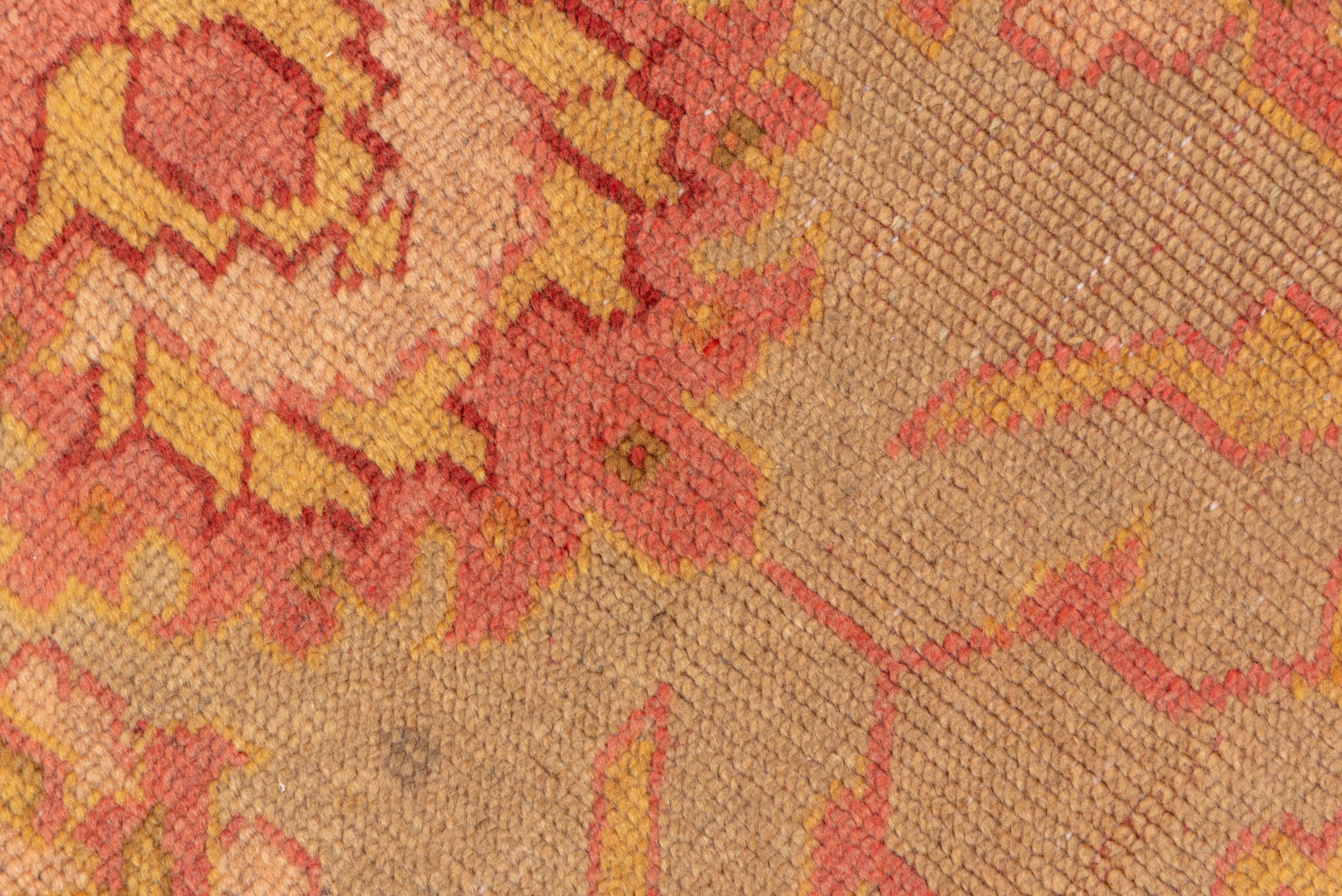 The peach field displays a centrally positioned spacious design of rough palmettes and fringed acanthus leaves, accented in goldenrod, pale tangerine, rust and green. Pale pink border with palmettes, tilted in the corners. Coarse weave, vlongish