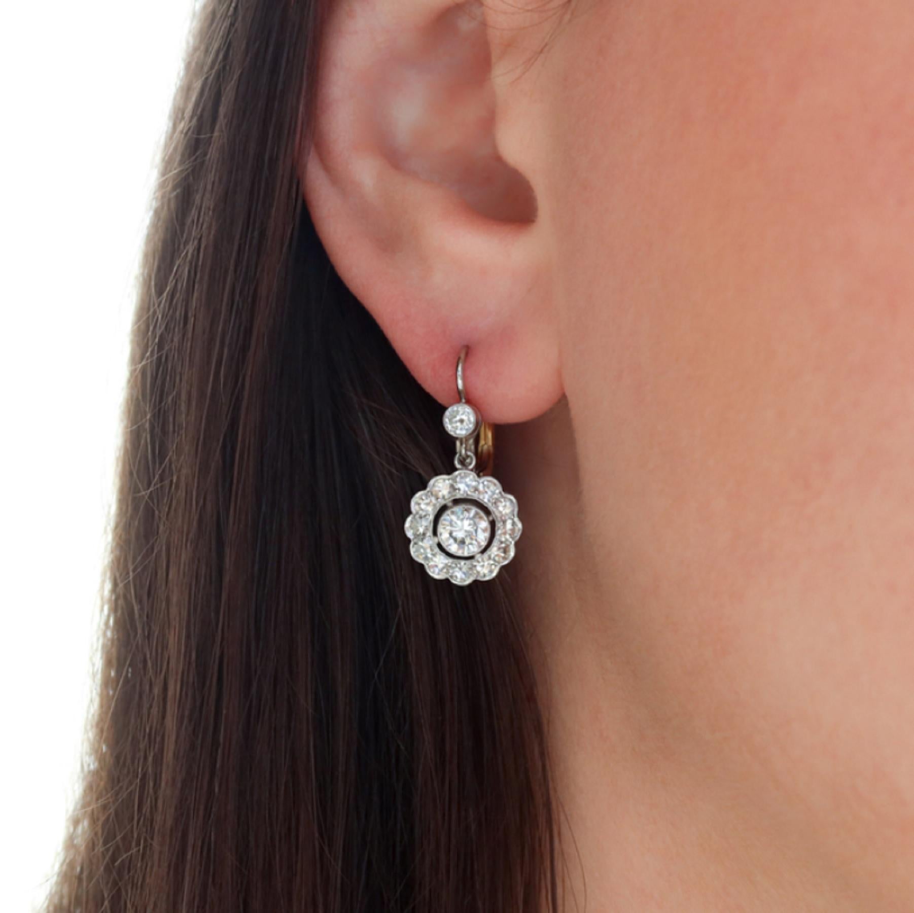  A breathtaking pair of authentic vintage dangle earrings feature two vibrant round brilliant cut diamonds surrounded by sparkling halos of high quality vintage one cut diamonds. 

Totaling 0.84 carats the two center diamonds are crisp white and