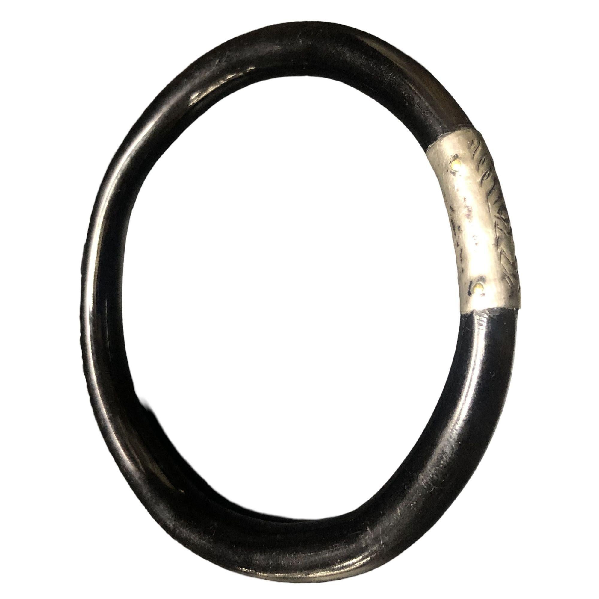 Black Bakelite bangle bracelet with sterling silver band adornment.

Measures: 2 3/8
