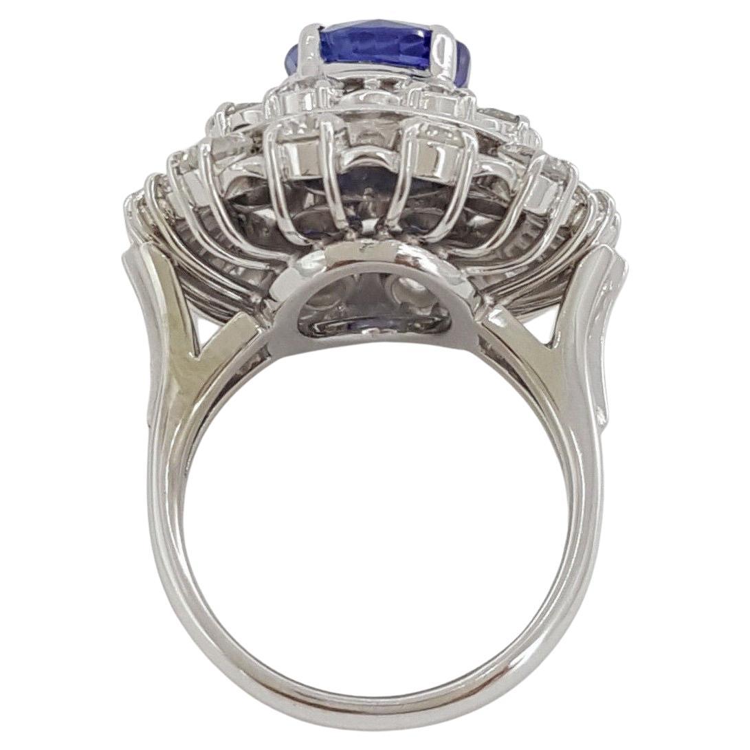 Bague de cocktail vintage en platine avec saphir bleu ovale, diamant rond brillant et baguette en double halo. 





