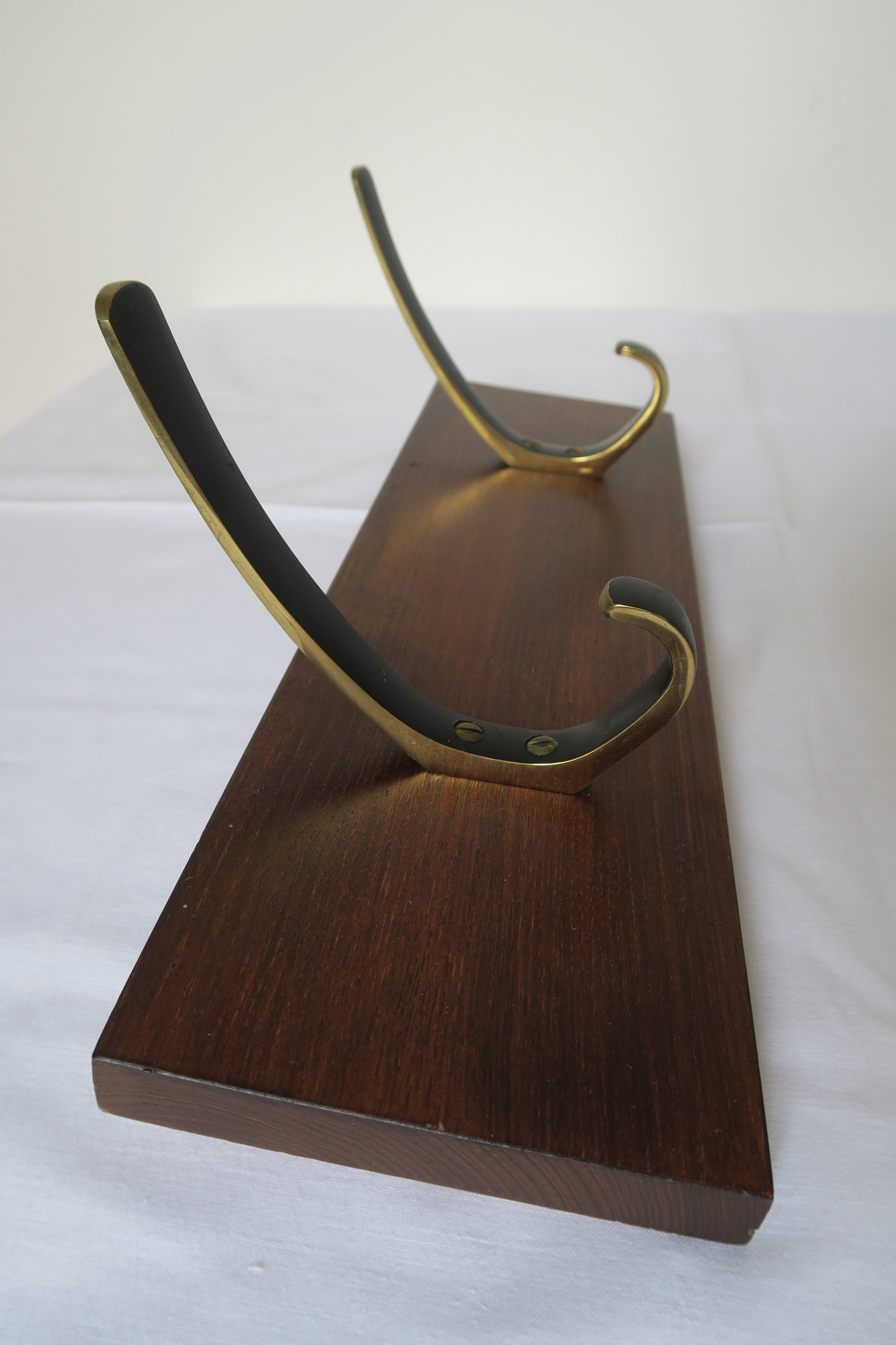 This coat rack is an authentic piece designed and crafted by the Austrian Werkstätten Of Herta Baller, probably designed by Walter Bosse. It was made using the finest materials, in this case beautiful medium-dark wood and brass hooks and screws. The