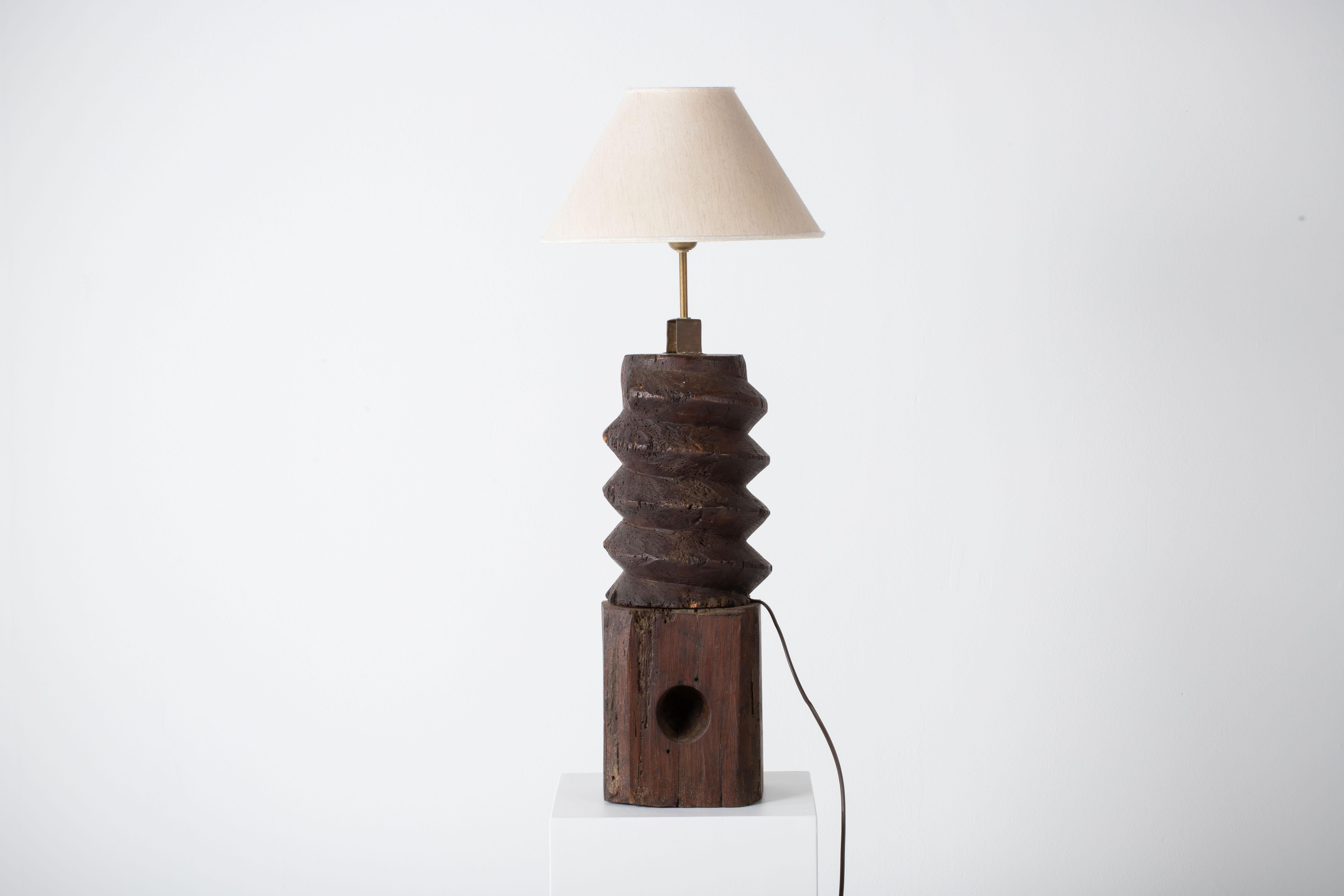 Voici une lampe de table extraordinaire qui allie harmonieusement l'esthétique brutaliste et l'artisanat authentique. Cette pièce unique a été fabriquée à partir d'un ancien pressoir à vin, transformé en un luminaire visuellement