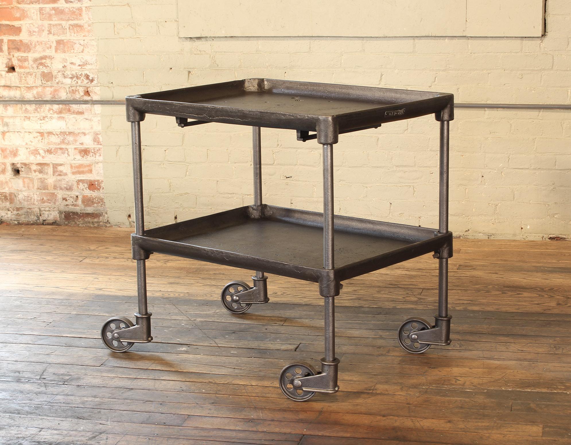 Authentic vintage industrial two-tier cast iron rolling tool / bar cart or side / end table. Features adjustable height shelf and four cast iron 4 1/2