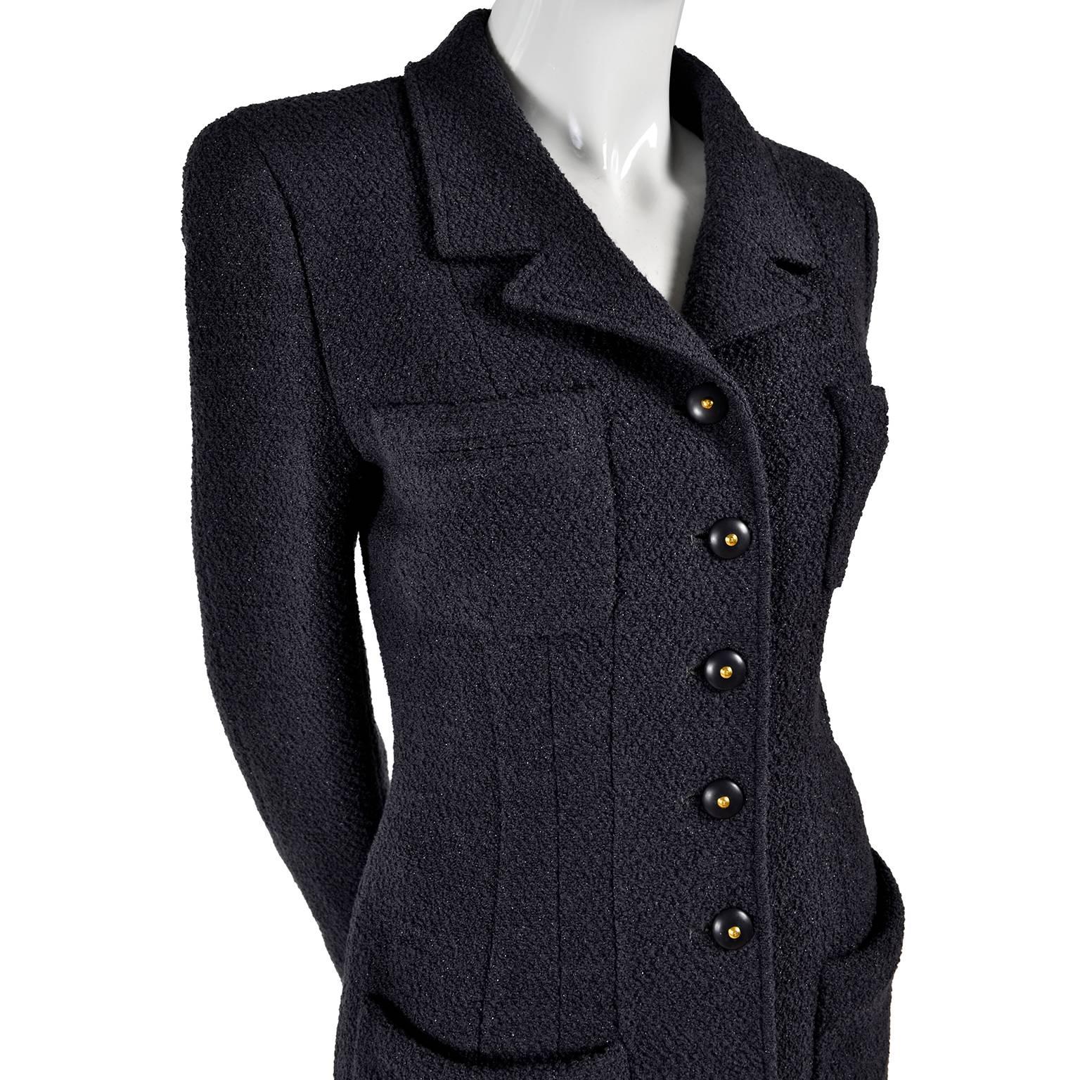 This is a stunning charcoal gray Chanel skirt suit with shimmering sparkles woven throughout the wool tweed. It has a five button jacket, with two breast pockets and two pockets at the hips, with slits in front as an added style element. The jacket