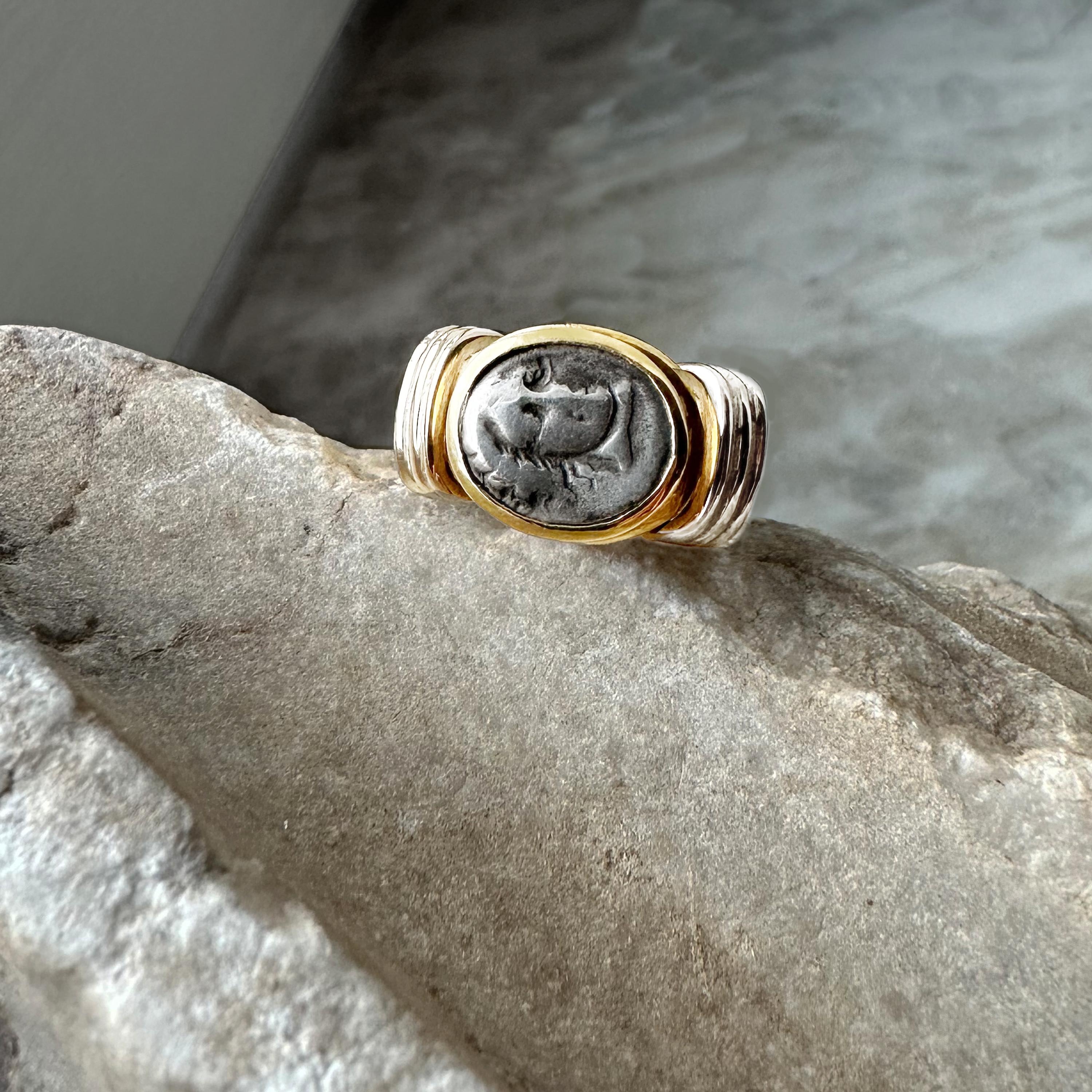 In this 18 Kt gold ring there is mounted an authentic silver coin ( 4th century B.C.) depicting Helios; in the other side of the coin there is a Rose.

Helios (identified with Apollo) was adopted as the patron diety of Rhodes upon the city's
