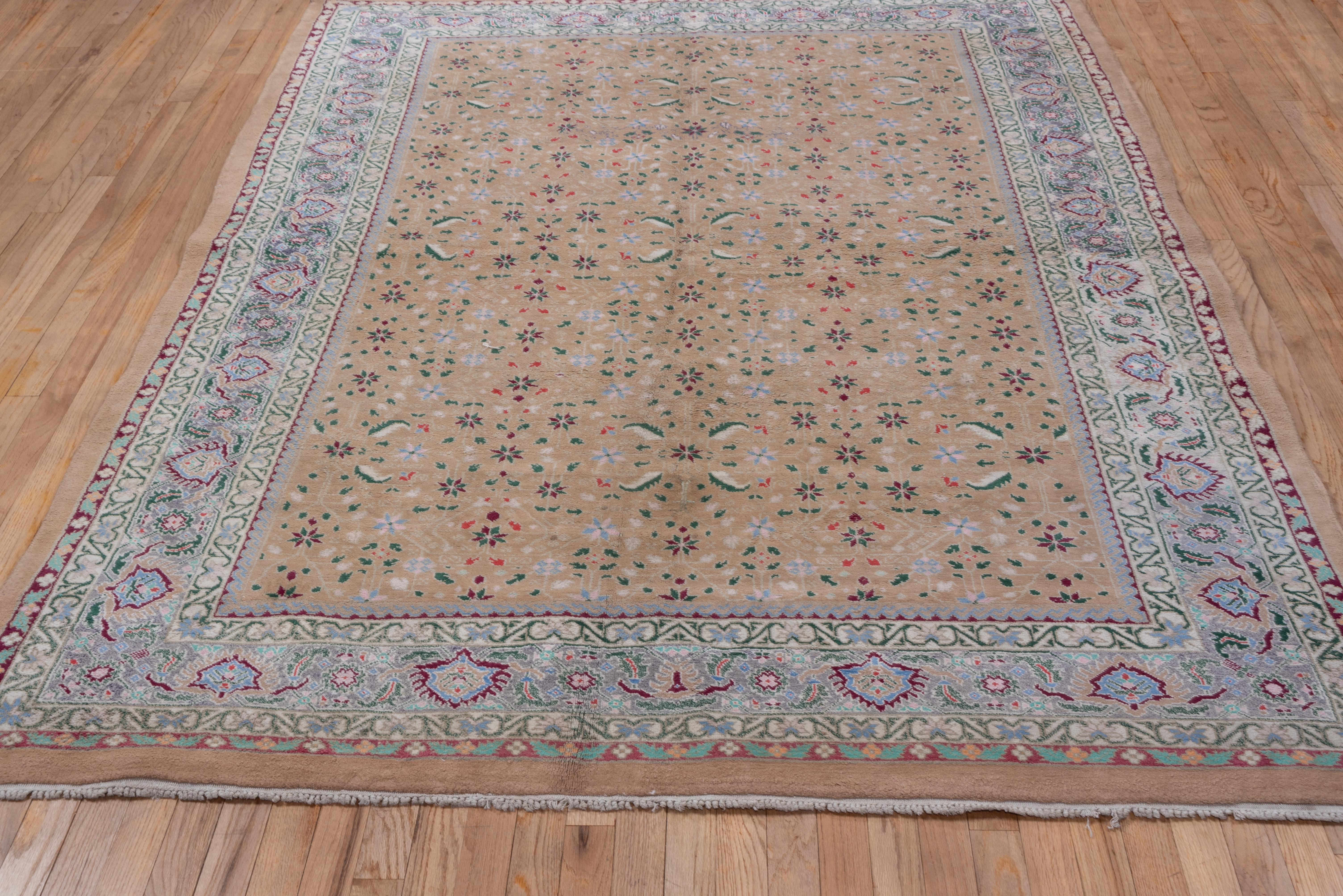 This northern Indian town carpet presents a buff field with a repeating all-over pattern of small stars, lancet leaves and still stems, detailed in ecru, pale blue and dark brown. The main border abrashes in blue tones and exhibits a flaming