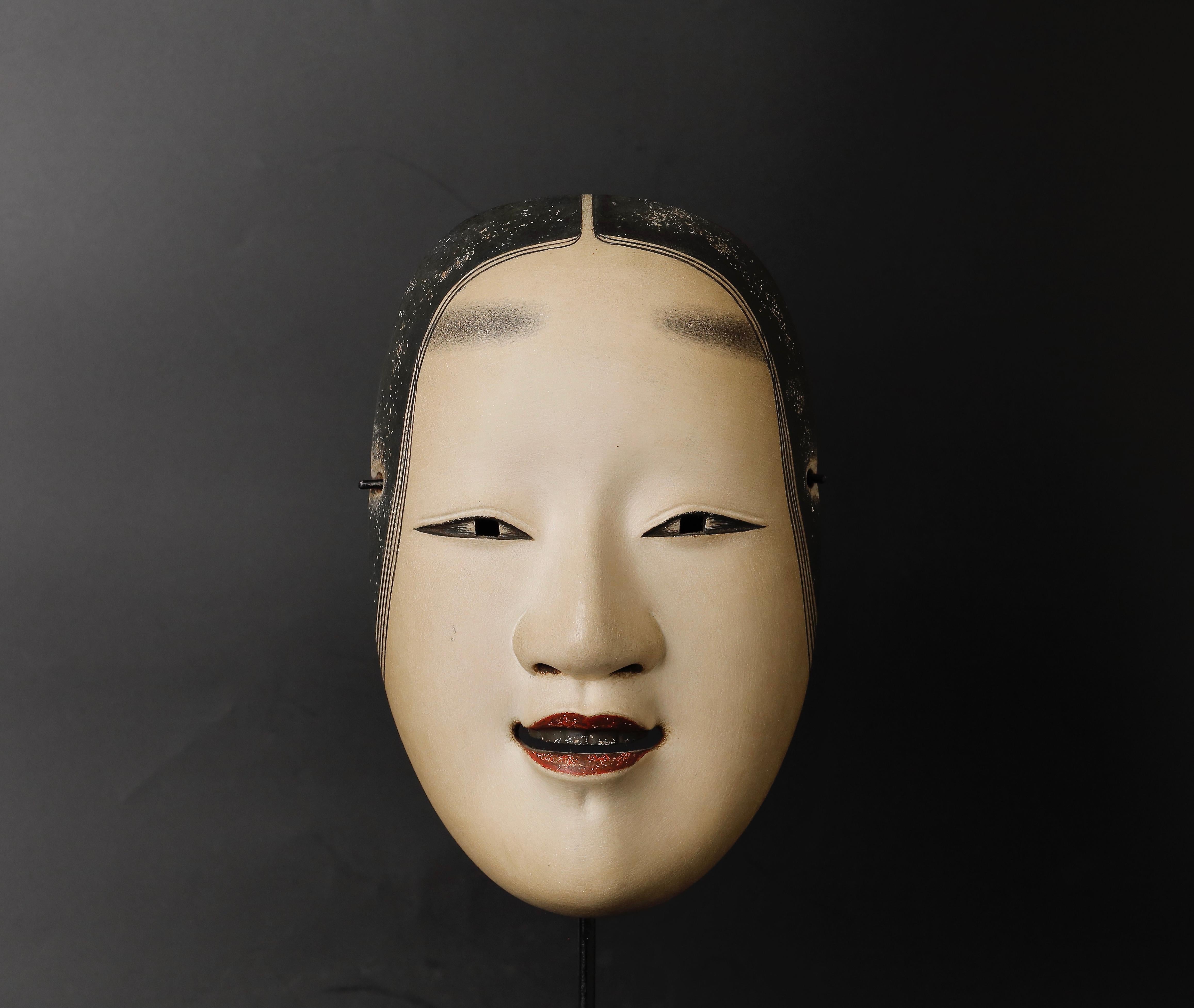 This stunning Japanese Noh mask depicts the Koomote character of a young woman who has not yet reached the age of twenty. Crafted from wood and painted with gofun, this mask is a true work of art.

Dating back to the 20th century, this Noh mask