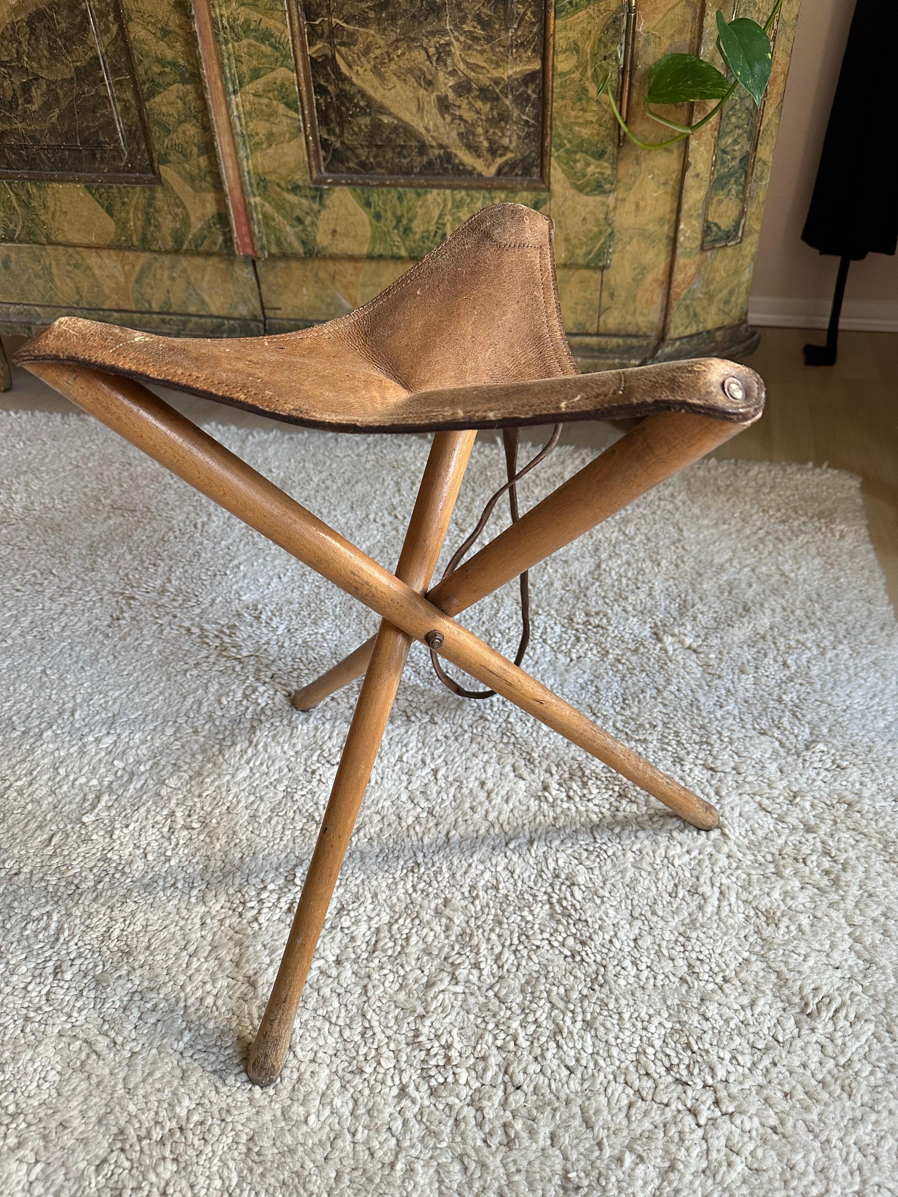 Step into the past with this vintage leather tripod stool from the 1920s. Whether on a hunting trip, outdoor excursion, or plein air painting session, this type of stool was a beloved companion for adventurers of yesteryear. Crafted with durable