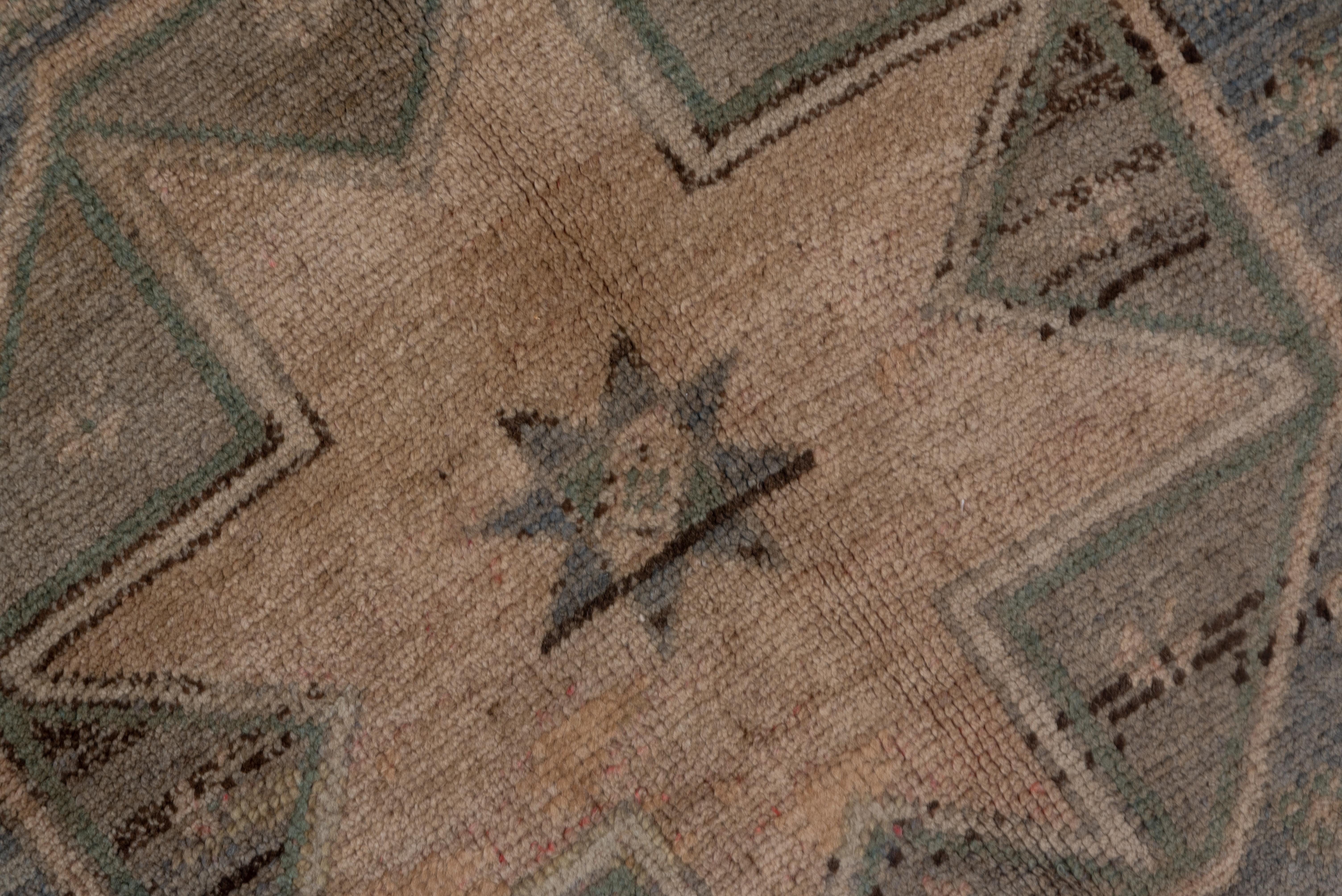 This Oushak Gallery Carpet has a tile pattern border which is a characteristic of Mucur with its occasional aubergine accents, to the straw field with four hooked octagons with straw central star motives.