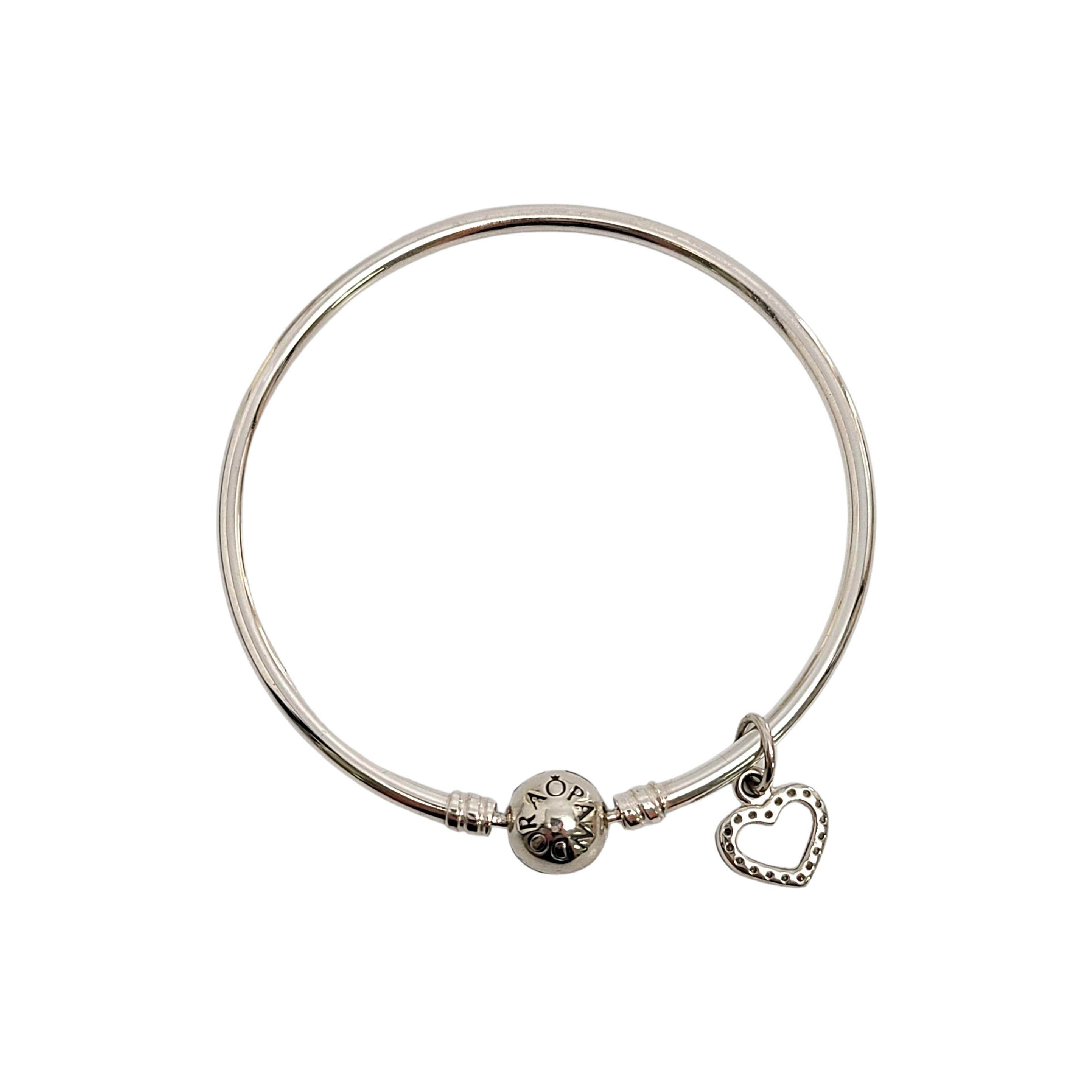 Pandora sterling silver bangle bracelet with CZ heart dangle.

Size 7.5

This lovely Pandora bangle bracelet features an open CZ heart dangling. Clip design closure.

Weighs approx 6.7dwt, 10.4g

Marked Pandora on clasp, S925 ALE inside clasp and on