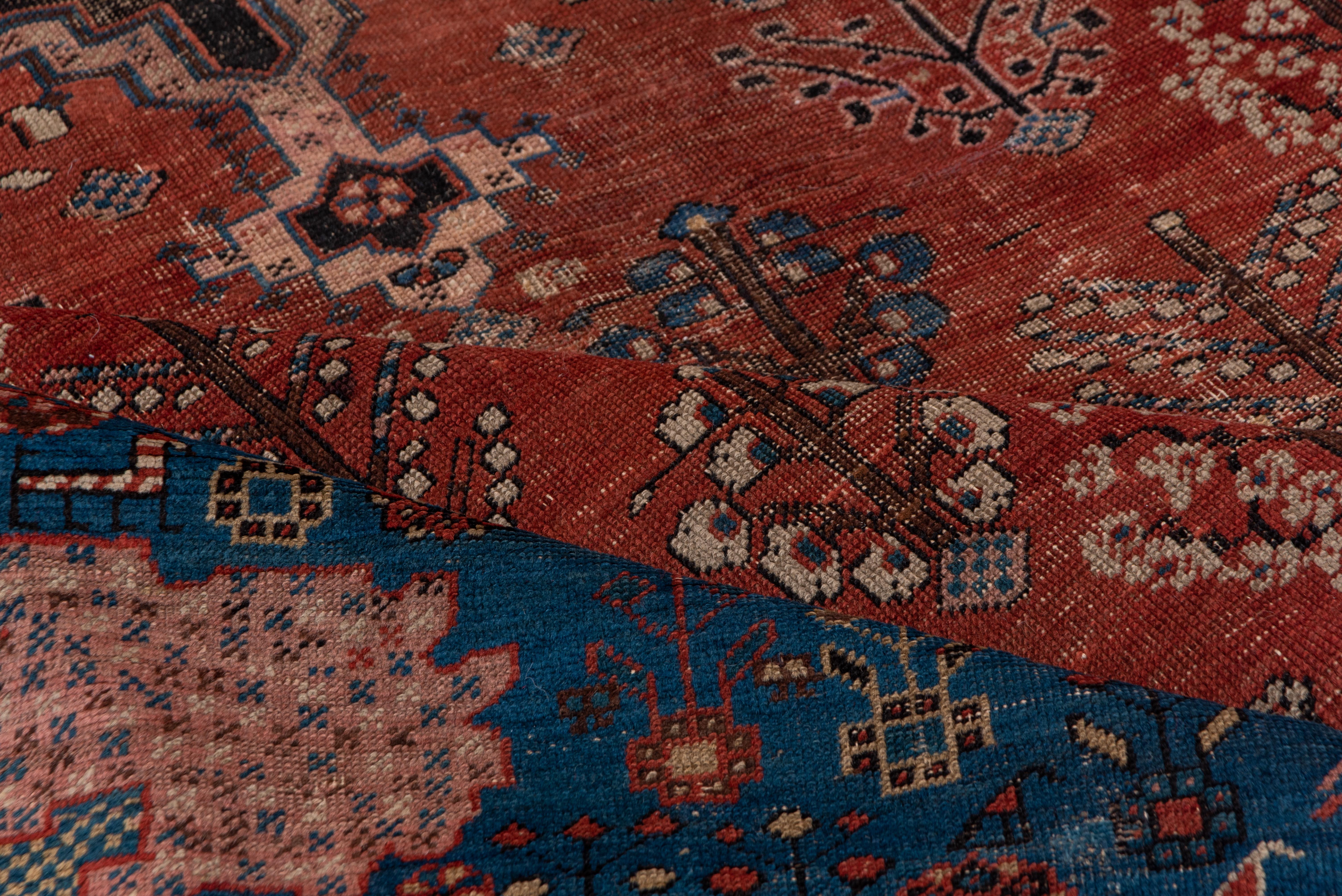 With a decidedly Caucasian palette of madder rust-red (Sub-field), light blue (field) and ivory (details) this antique NW Persian rural carpet shows Joshegan-like flower modules in the field around a navy stepped regular hexagon medallion enclosing