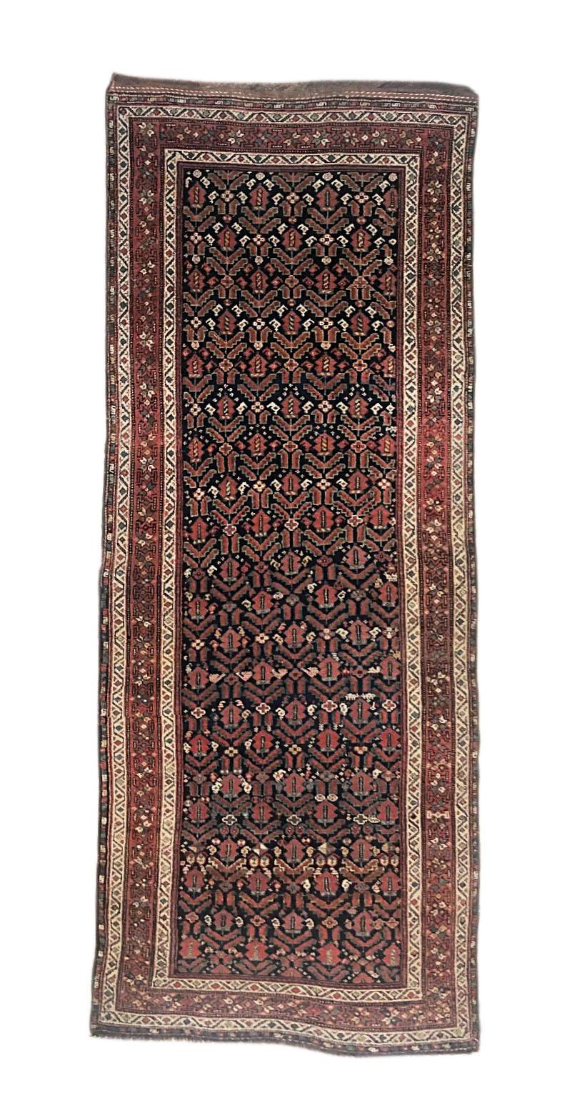 This antique rug is a Persian Kurdish with wool pile and wool foundation. The design is geometric all-over, circa 1940s. The size is 4 feet wide by 10 feet 6 inches tall.