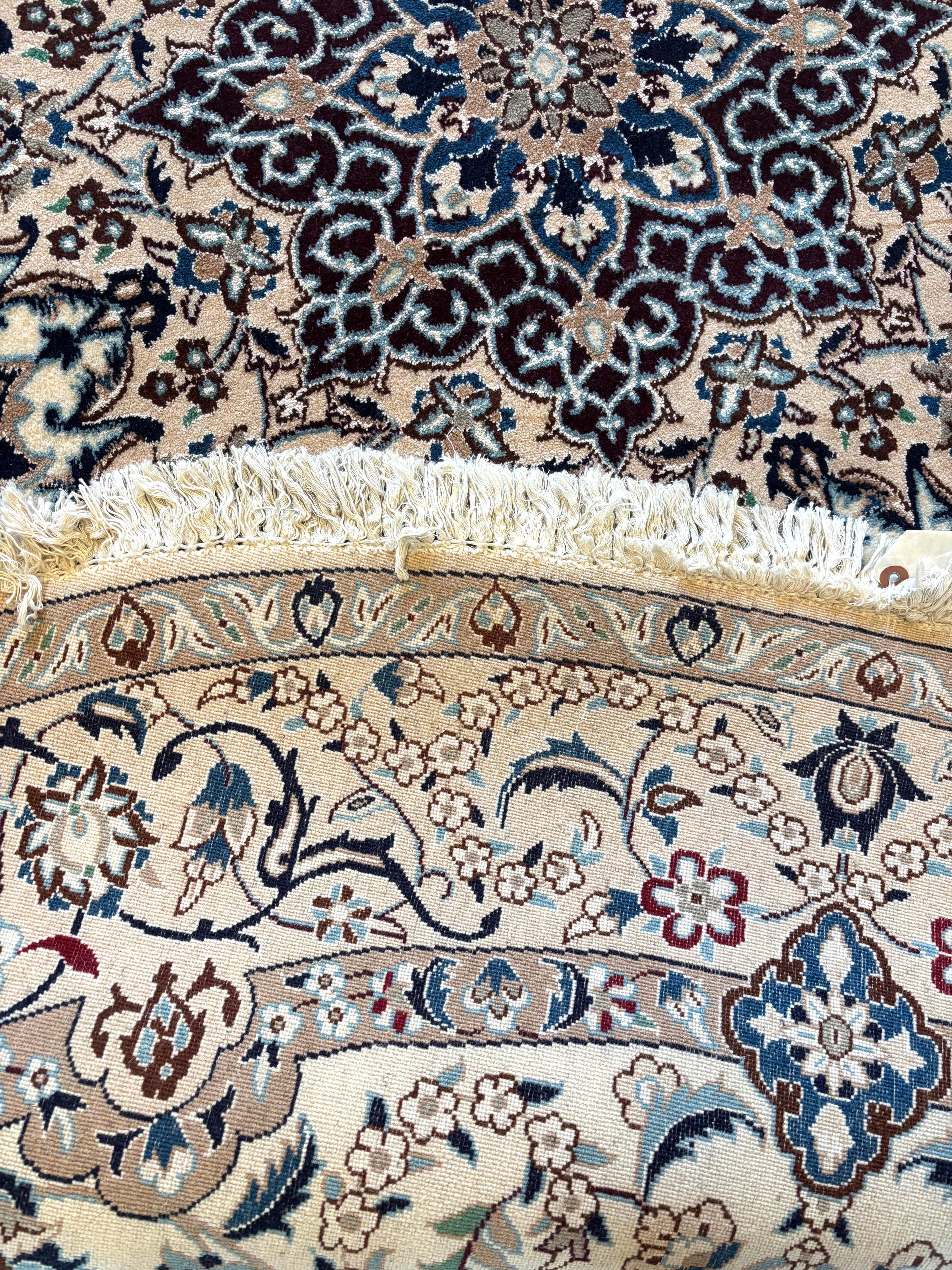 This authentic Persian round hand-made Nain 9 LAA (rug has high quality wool and silk pile with cotton foundation. The silk highlights the detail in the design. Nain is a city in Iran that is well known for producing fine handmade rug. This rug has