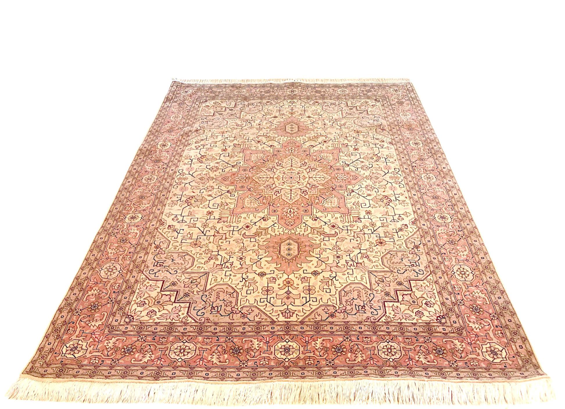 This Persian Tabriz (Heriz Design) rug has wool and silk pile and cotton foundation. This rug has a geometric design. The base color is cream with salmon-pink border color. The size is 4 feet 11 inch wide and 6 feet 6 inch long. This piece has been