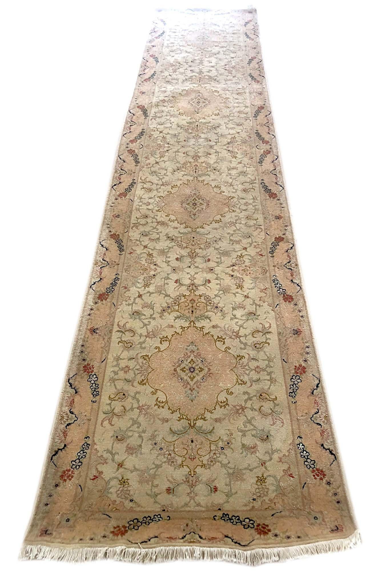This Persian Tabriz runner has wool & silk pile and cotton foundation. This rug features a beautiful floral rug pattern that has cream base color with light peach border. The size is 2 feet 10 inch wide and 10 feet 1 inch long. This piece has been