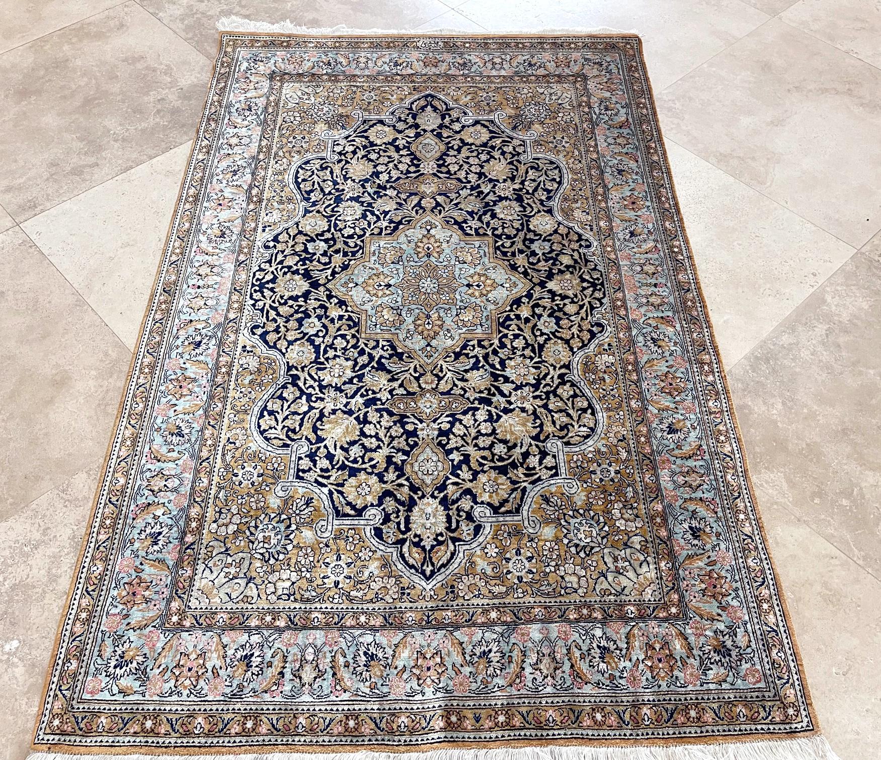 This is a very fine rug weaved in city of Qum, Iran. This rug has silk pile and foundation, with a stunning design and color combination woven onto a dark blue background with a turquoise border. The design in this piece is a medallion semi floral