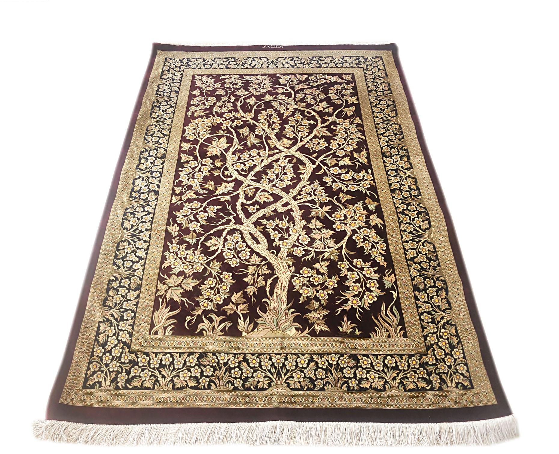 This is an extremely fine rug is weaved in city of Qum, Iran. This rug has silk pile and foundation, with a dramatic tree of life design woven onto a burgundy background with a dark blue border. The tree of life is a popular element in many vintage