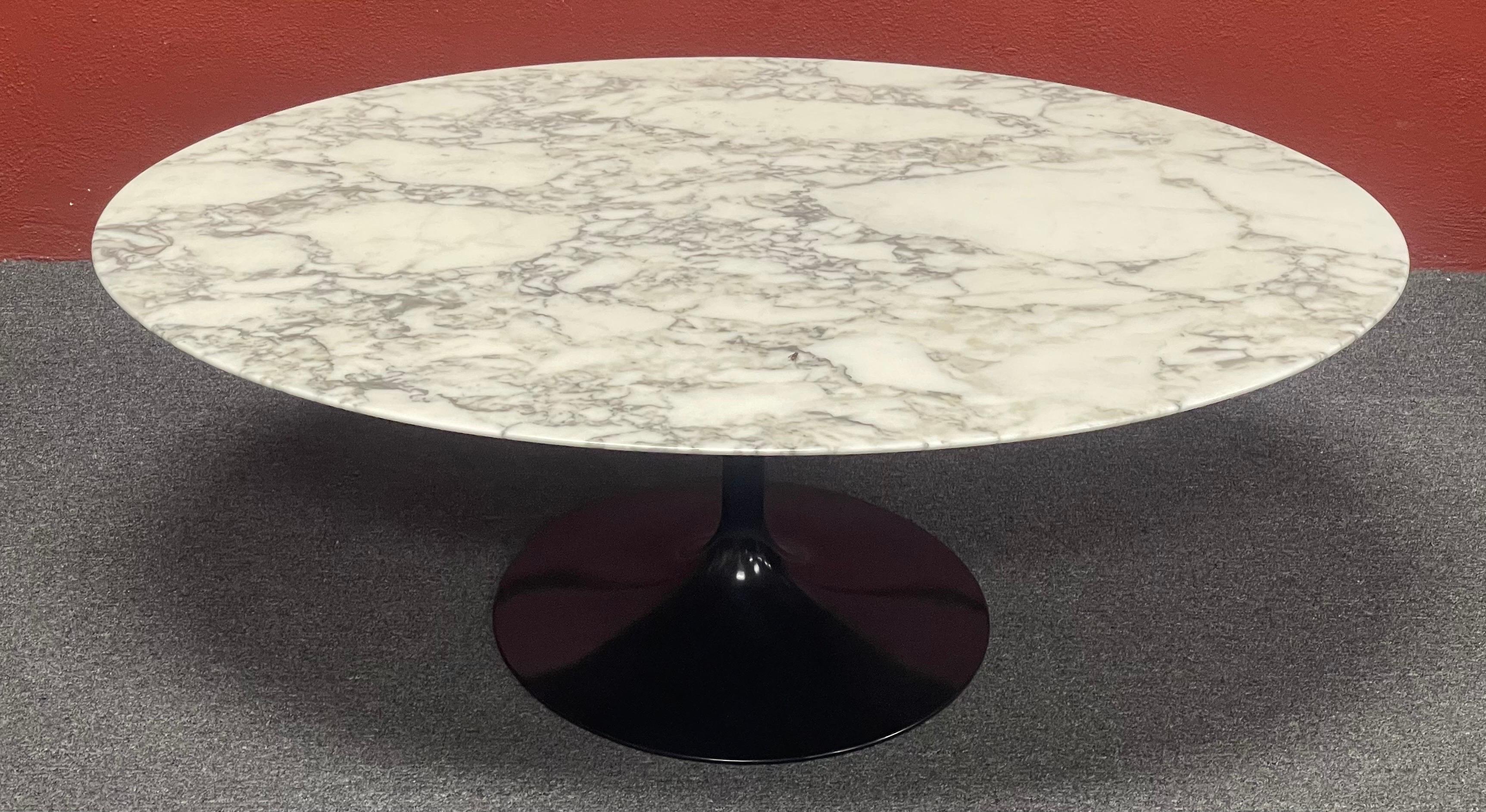 Authentic polished carrara marble top coffee table with black aluminum cast base by Eero Saarinen for Knoll, circa 2015. This timeless modern classic has been in continuous production since 1956. This sturdy table is in very good condition and