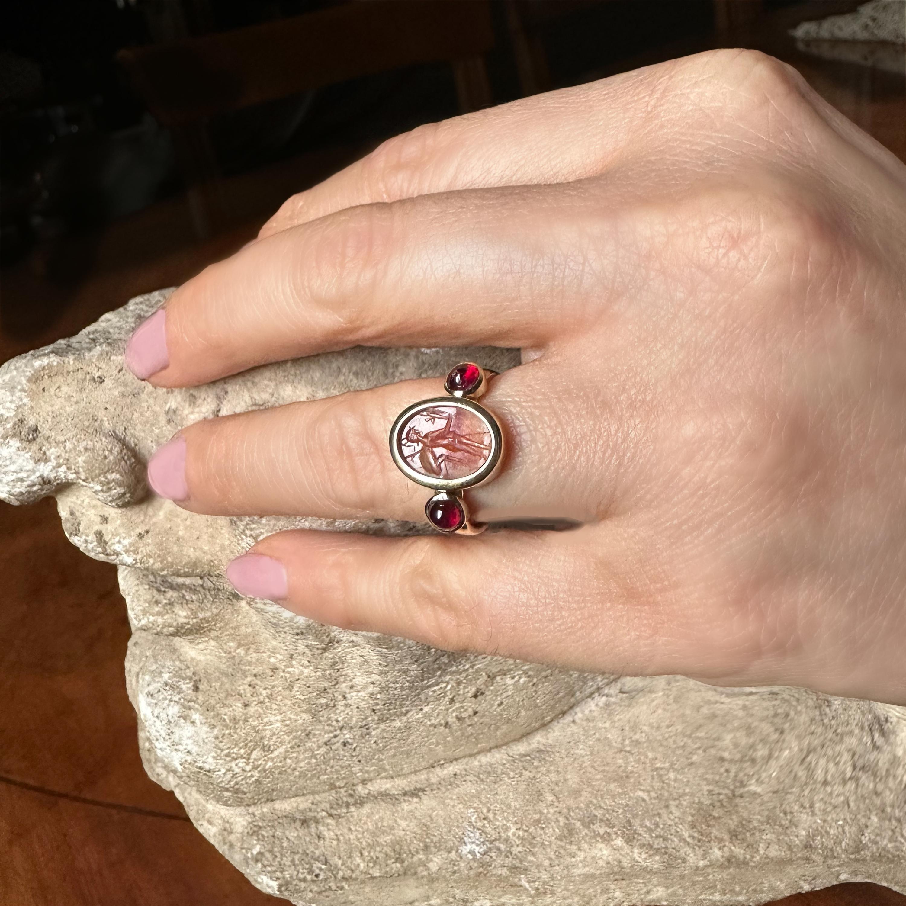 <p>Dieser Ring aus 18-karätigem Gold zeigt einen echten römischen Karneol aus dem 1. bis 2. Jahrhundert n. Chr. mit der Darstellung der Göttin Athena Nicephora. Das römische Intaglio wird von zwei Cabochon-Rubinen flankiert. Auf dem Karneol steht