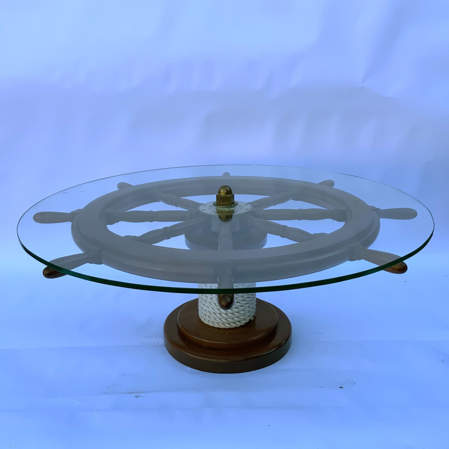 Genuine mahogany ship's wheel with a brass hub. Varnished finish. Mounted to a rope bound circular base. Plate glass top with brass nut cap. This is a professionally built wheel suitable for use on any vessel today. Sturdy brass hub with ten merging