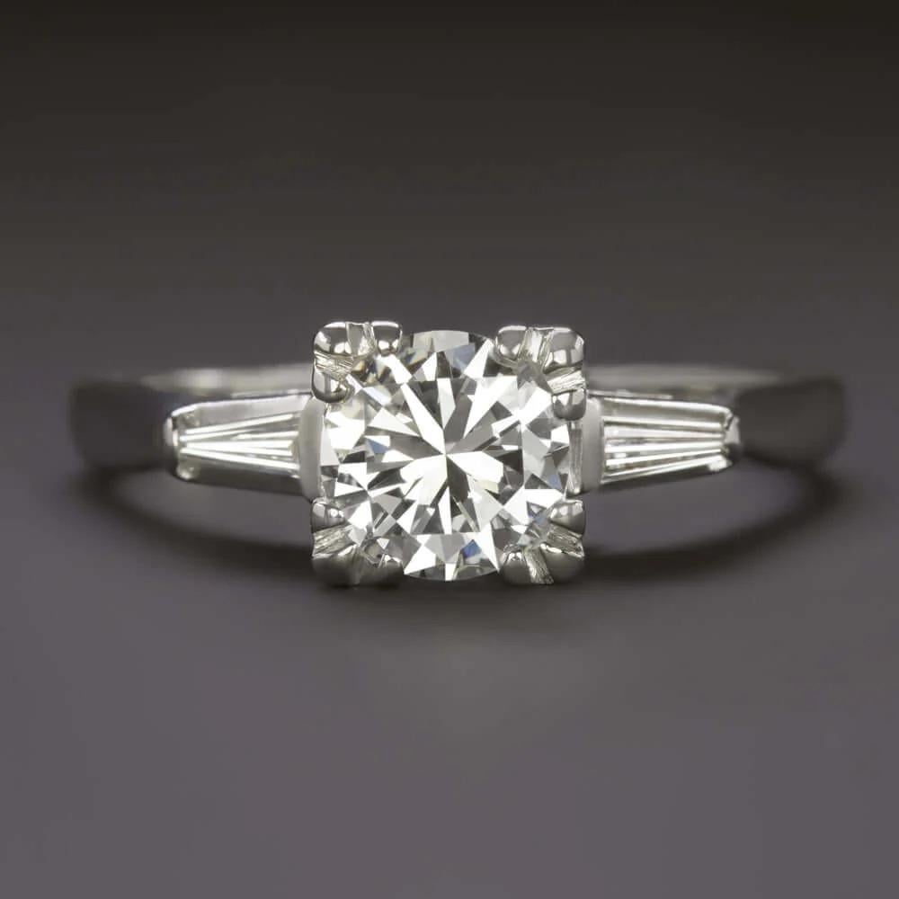 gorgeous and utterly classic vintage engagement ring combines eye catching impressive sparkle with an eternally stylish design. The 1 carat vintage round brilliant cut center diamond is bright white, completely eye clean, and sparkles with gorgeous