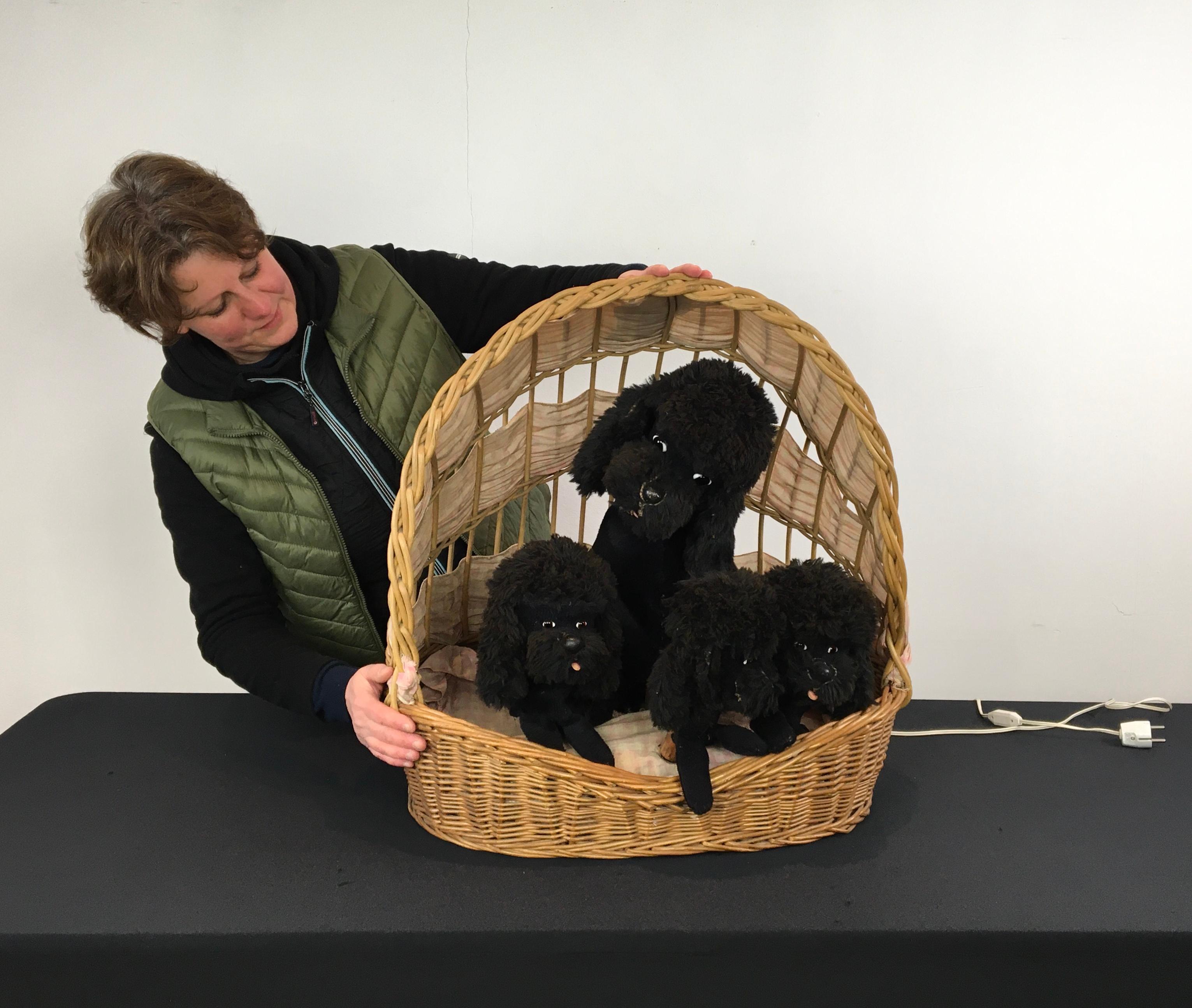 Automaton with dogs in a basket - poodles in rattan dog basket. 
A wicker basket filled with 4 black poodle dogs. 
A moving store display with 1 mama poodle and 3 puppies. 
The dogs are filled with straw, have mohair fur and glass eyes . 
They are