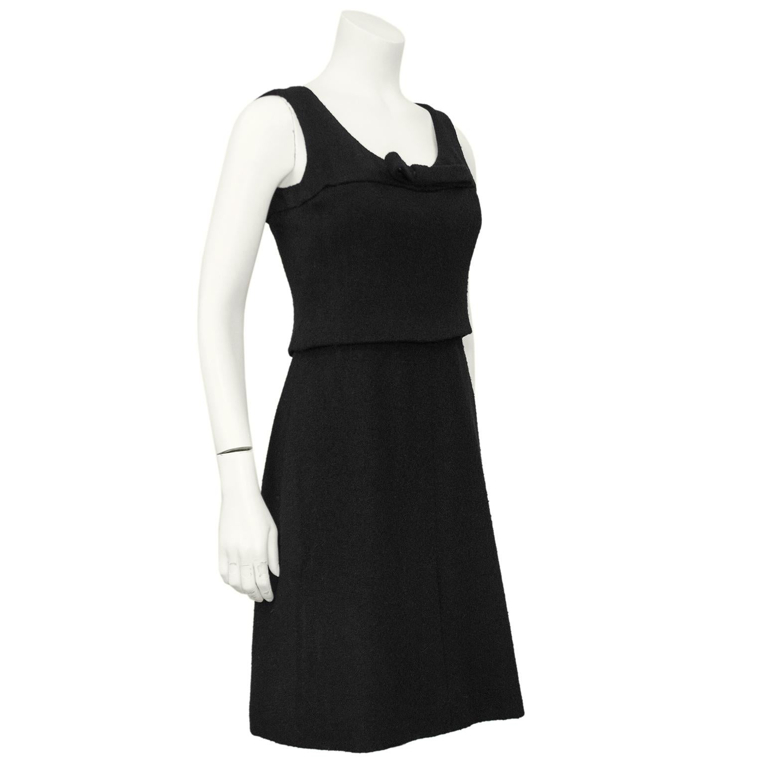 The most darling little black wool dress from the Autumn-Winter 1961 Christian Dior Haute Couture Collection by Marc Bohan. Sleeveless with a scoop neck with a large flat bow in the centre. The dress is constructed to look like a short top and a