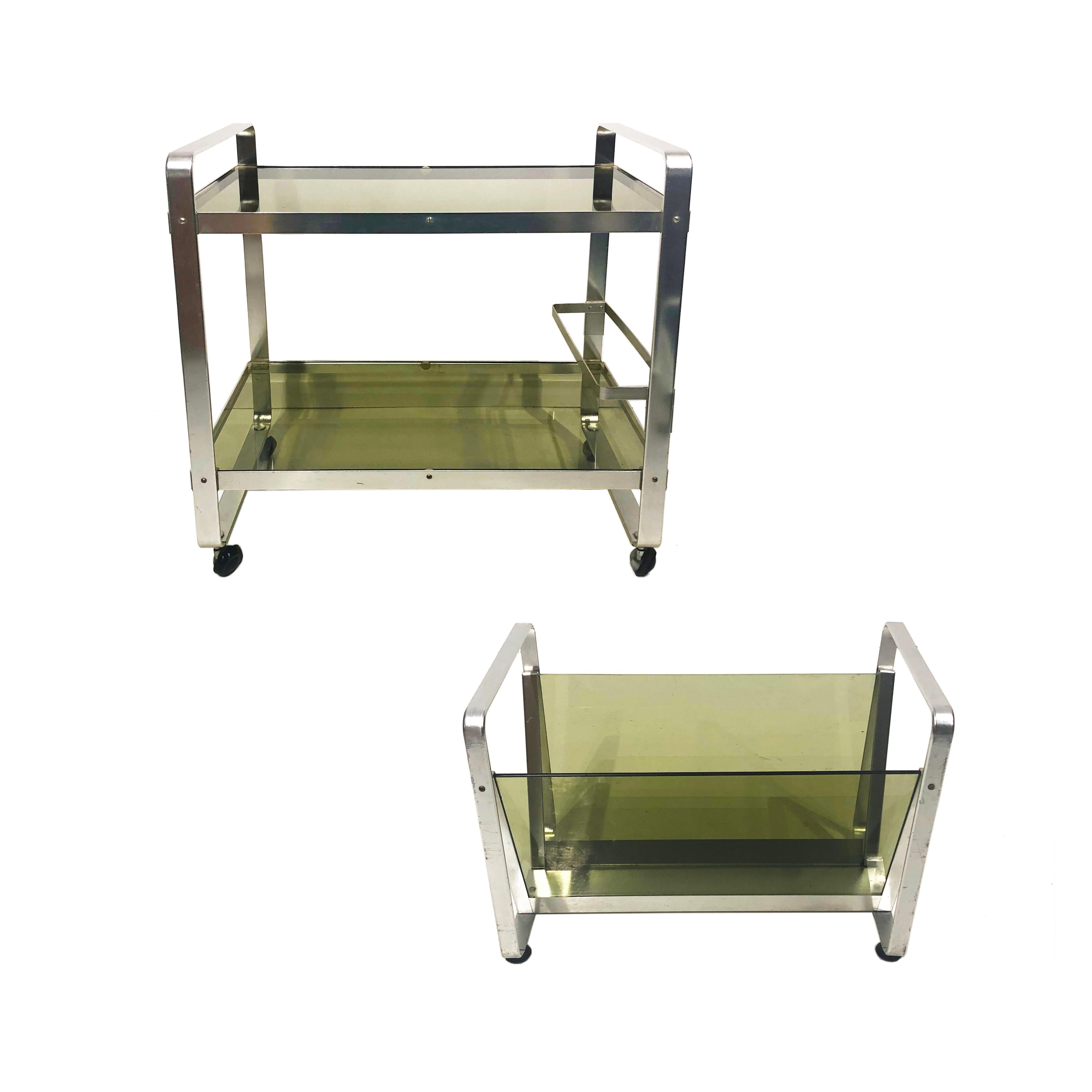Space Age drinks bar cart in silver aluminium bended metal frame and smoked green glass on wheels. Light weight and smooth to take around with the bottles bar changing height. AV Handwerk sticker at the bottom of the card.