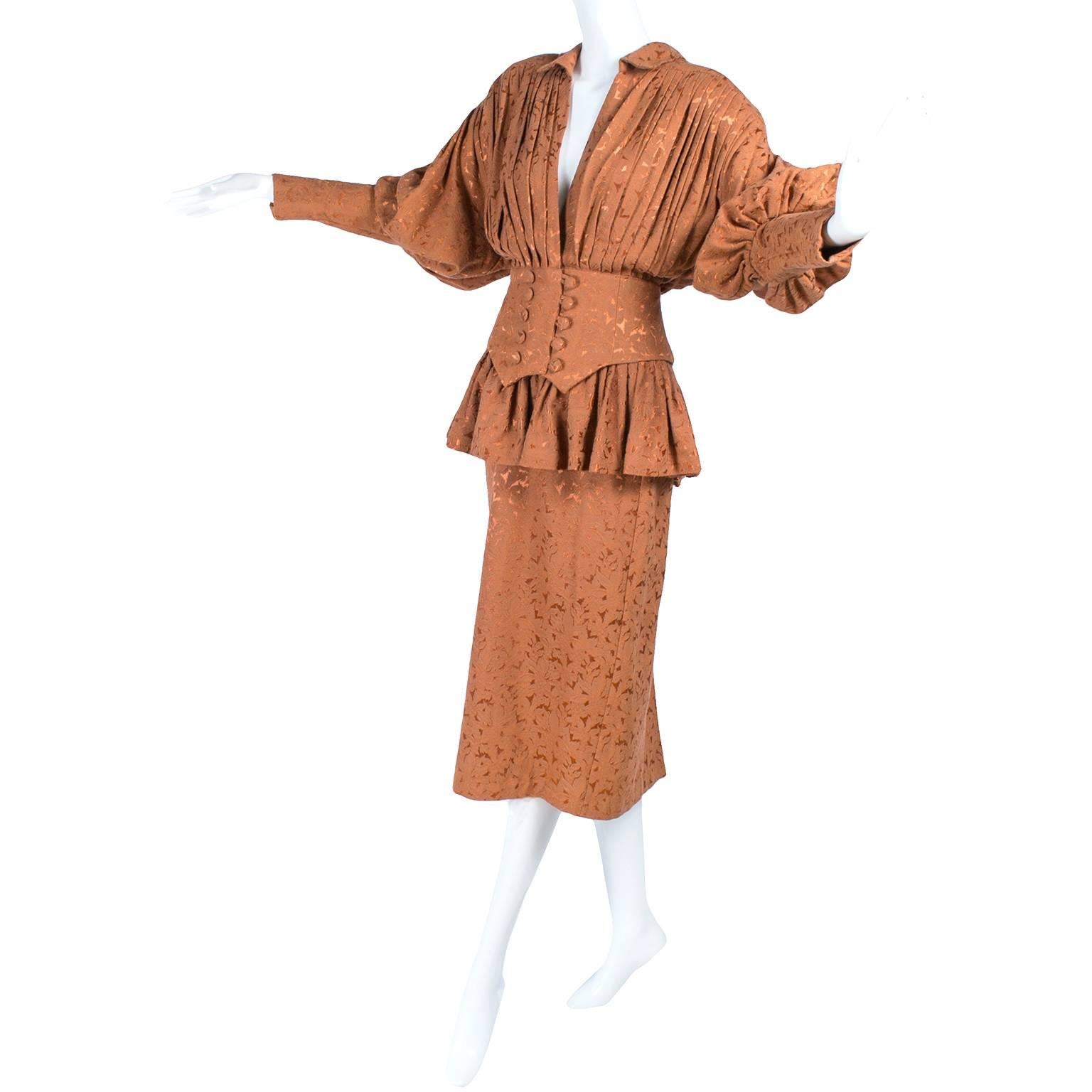 This is a rare Victorian style Norma Kamali skirt and jacket suit from the 1980's. This vintage Norma Kamali suit is iconic 1980's with shoulder pads and a cinched waist. The outfit is made in a copper jacquard fabric and the details are incredible.