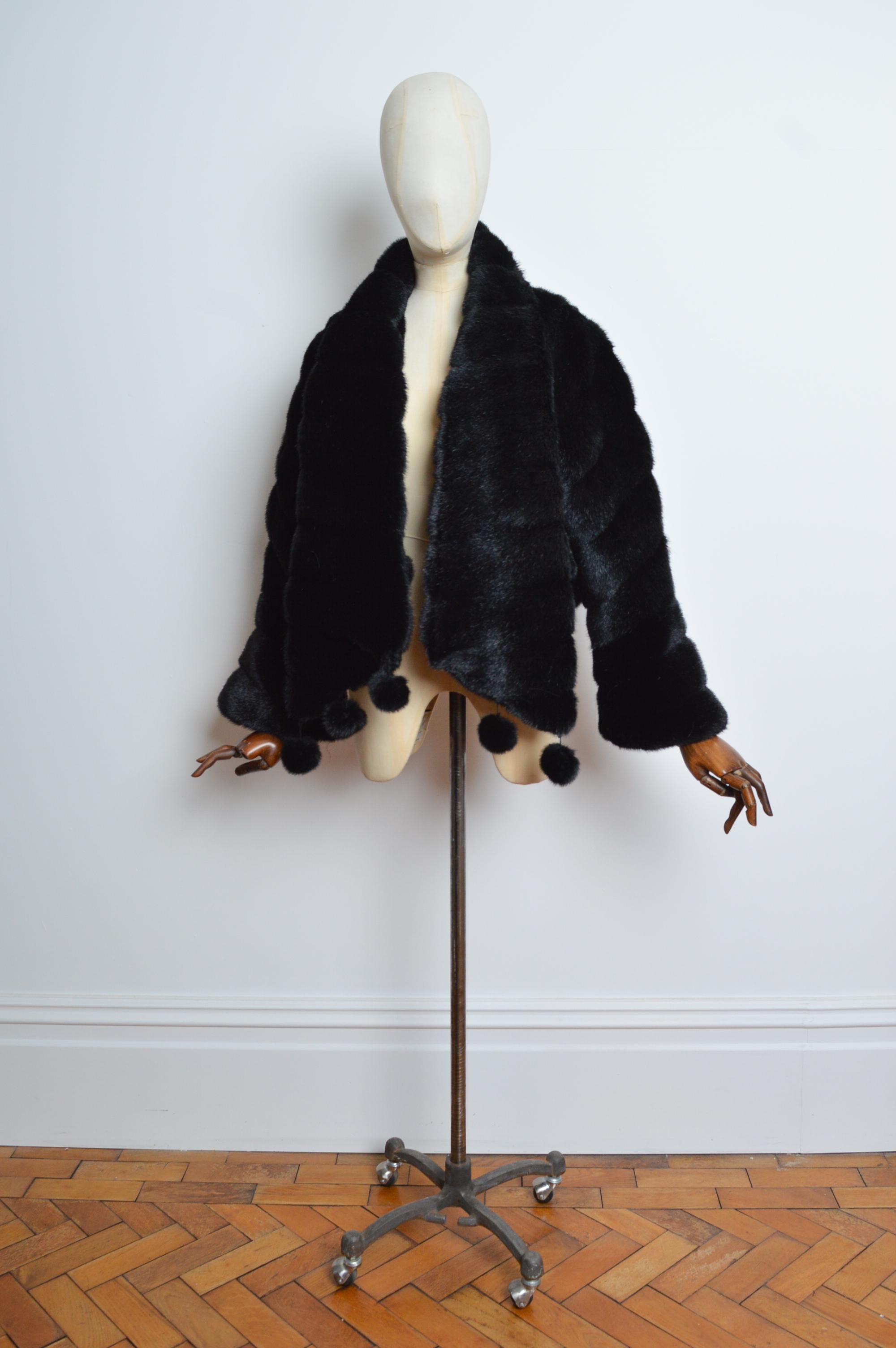 Fabulous Avant Garde 1990’s black cropped faux fur coat by Parisian label 'Comme du Vrai'. Made in France, featuring fluted sleeves, pompom trimmed hem, scarf like collar that can be styled in a multitude of ways and farrier hook closure. 
Size; One